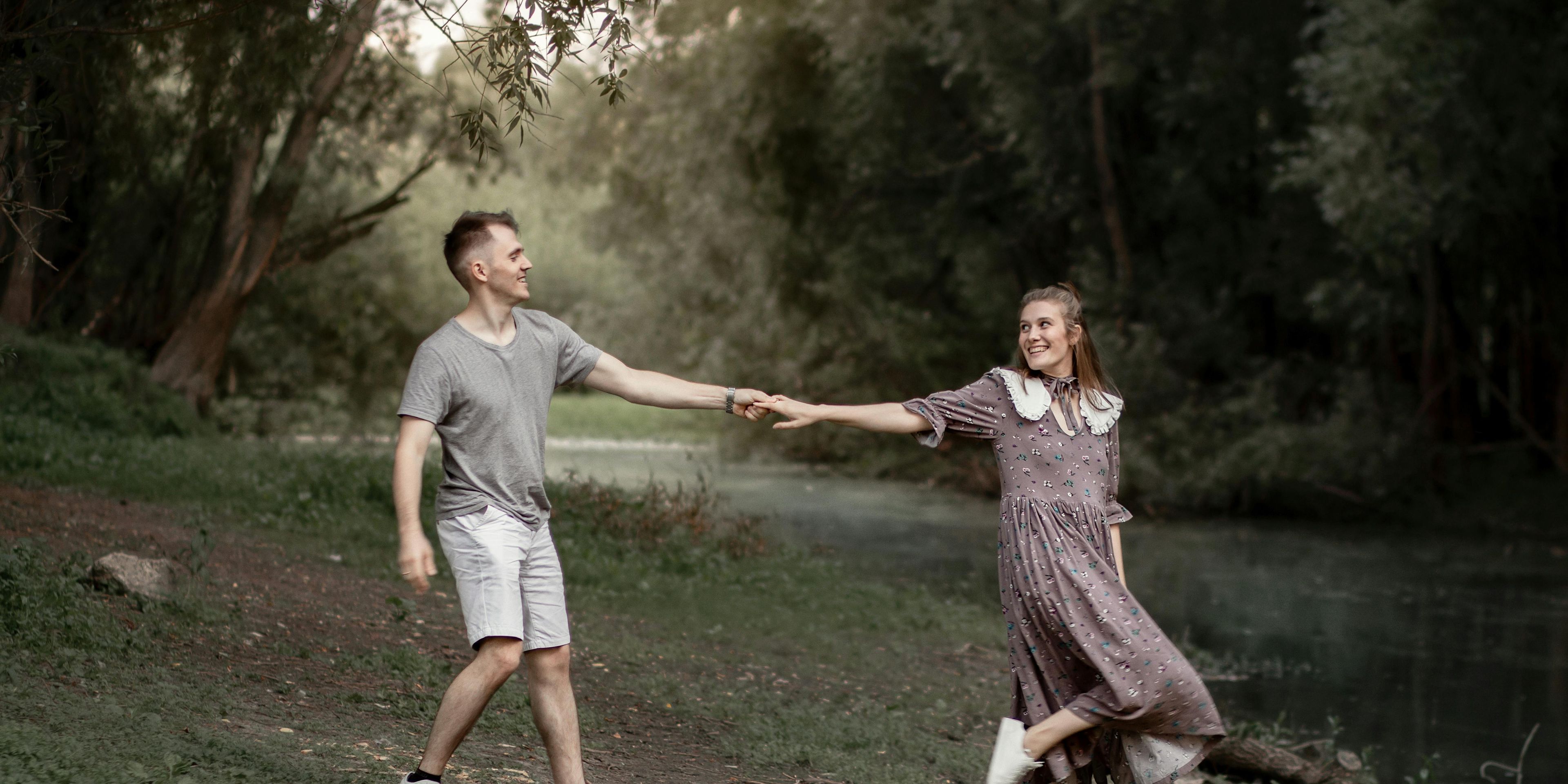 Young couple holding hands with the girl leading the boy in a nature area