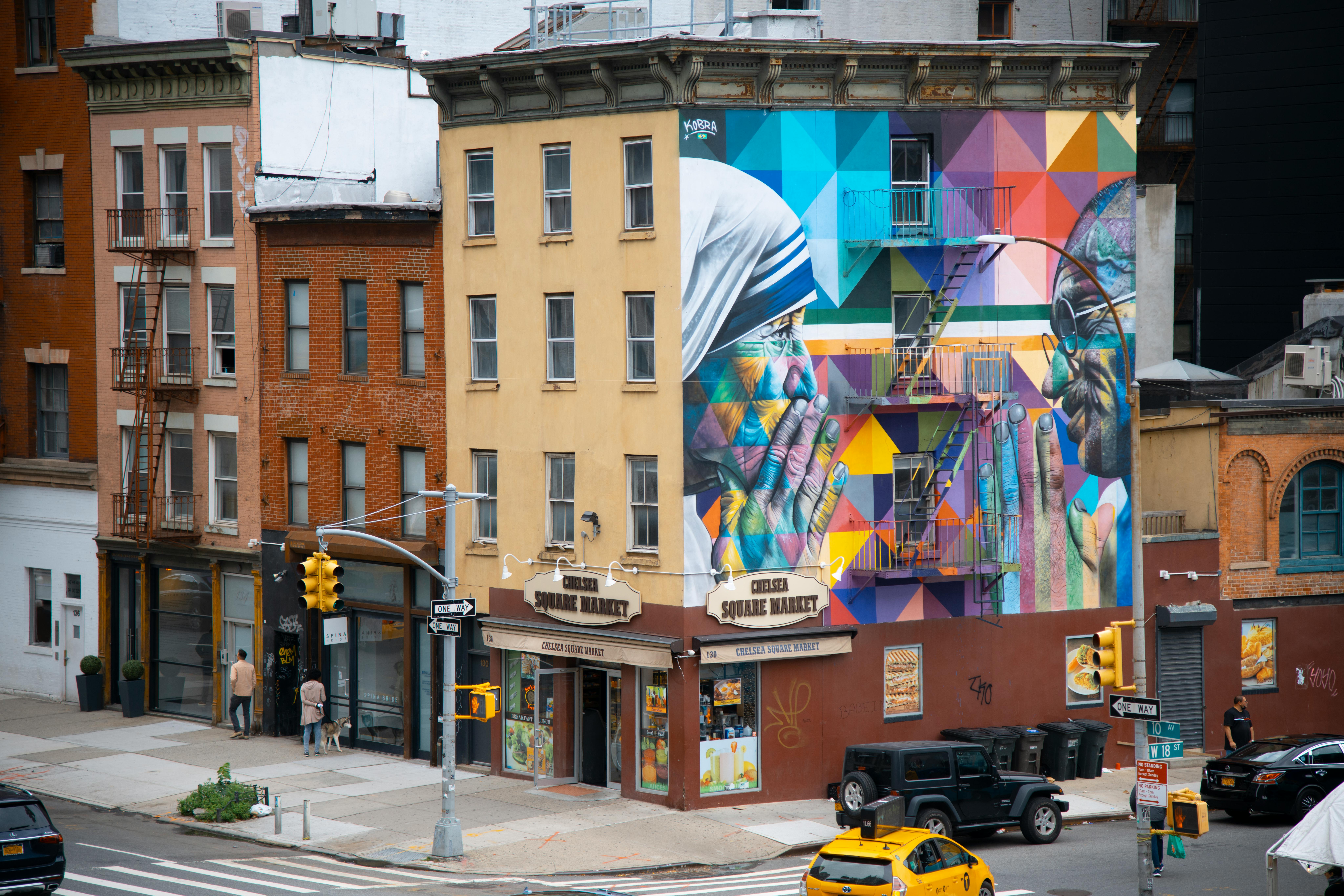 Brick buildings with one side of a building covered with a colorful geometric mural of Mother Theresa and Ghandi