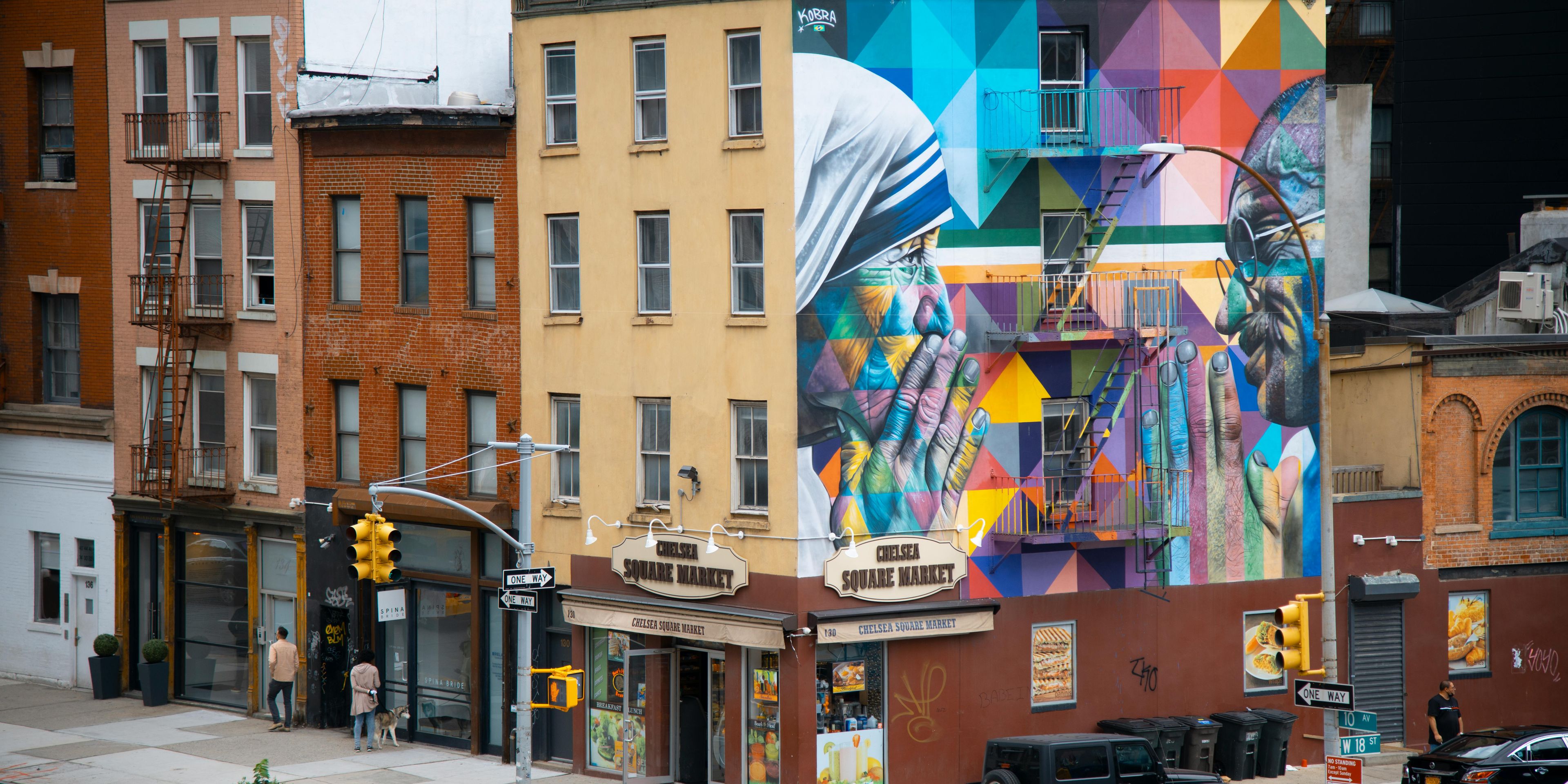 Brick buildings with one side of a building covered with a colorful geometric mural of Mother Theresa and Ghandi