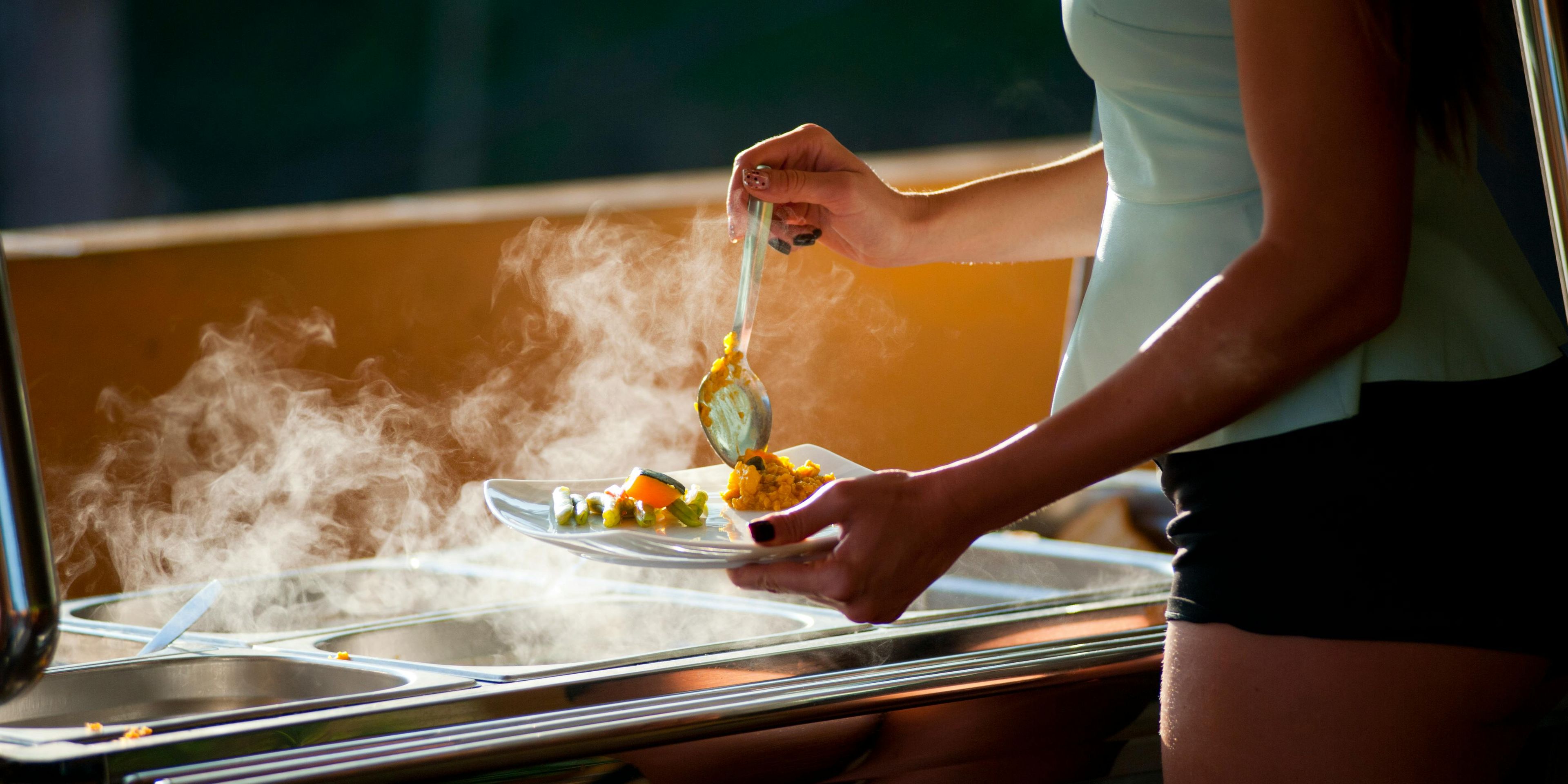 Woman at a buffet putting food on a plate