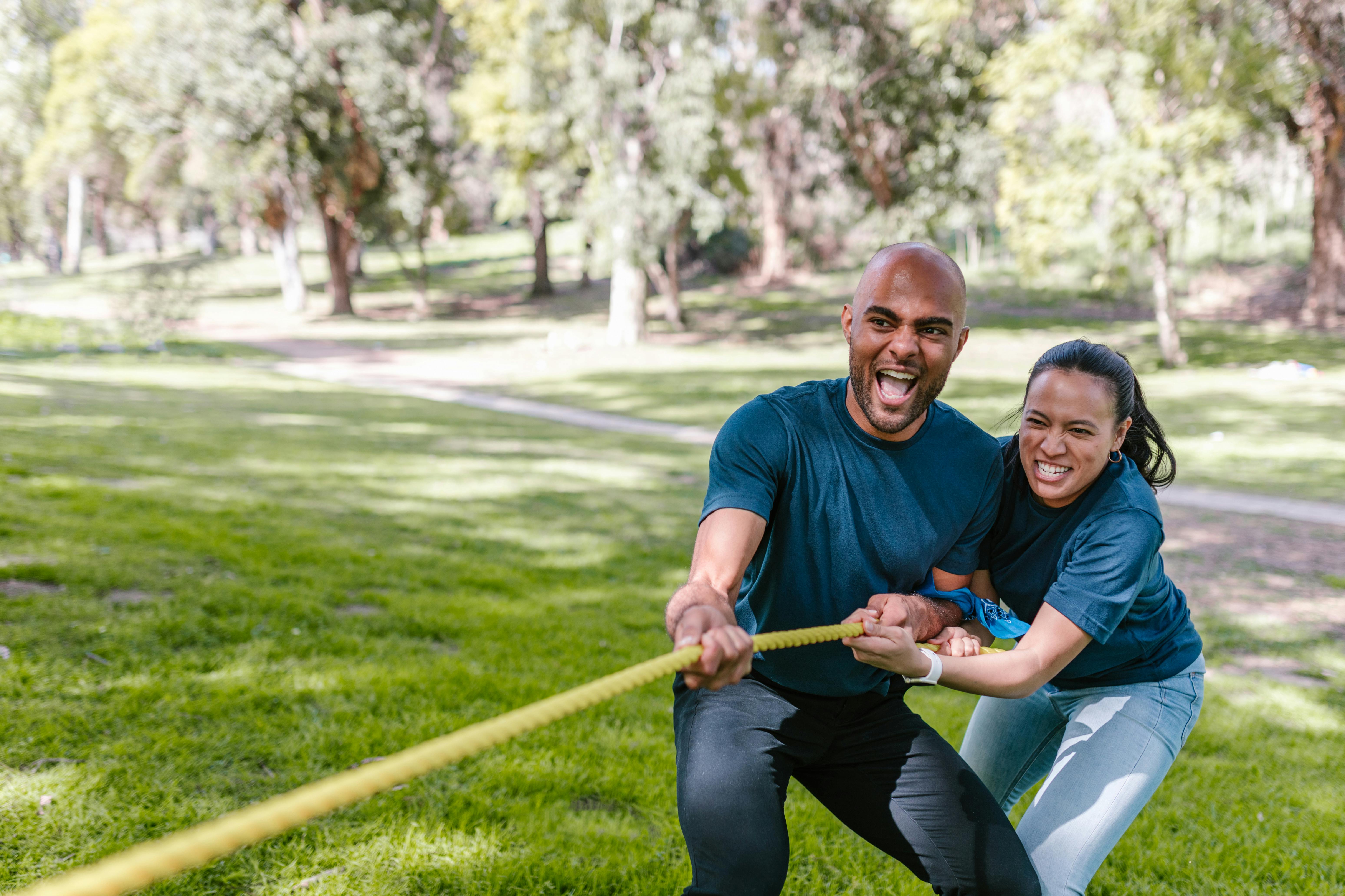 Couple with blue shirts and jeans pulling on a rope in tug-of-war