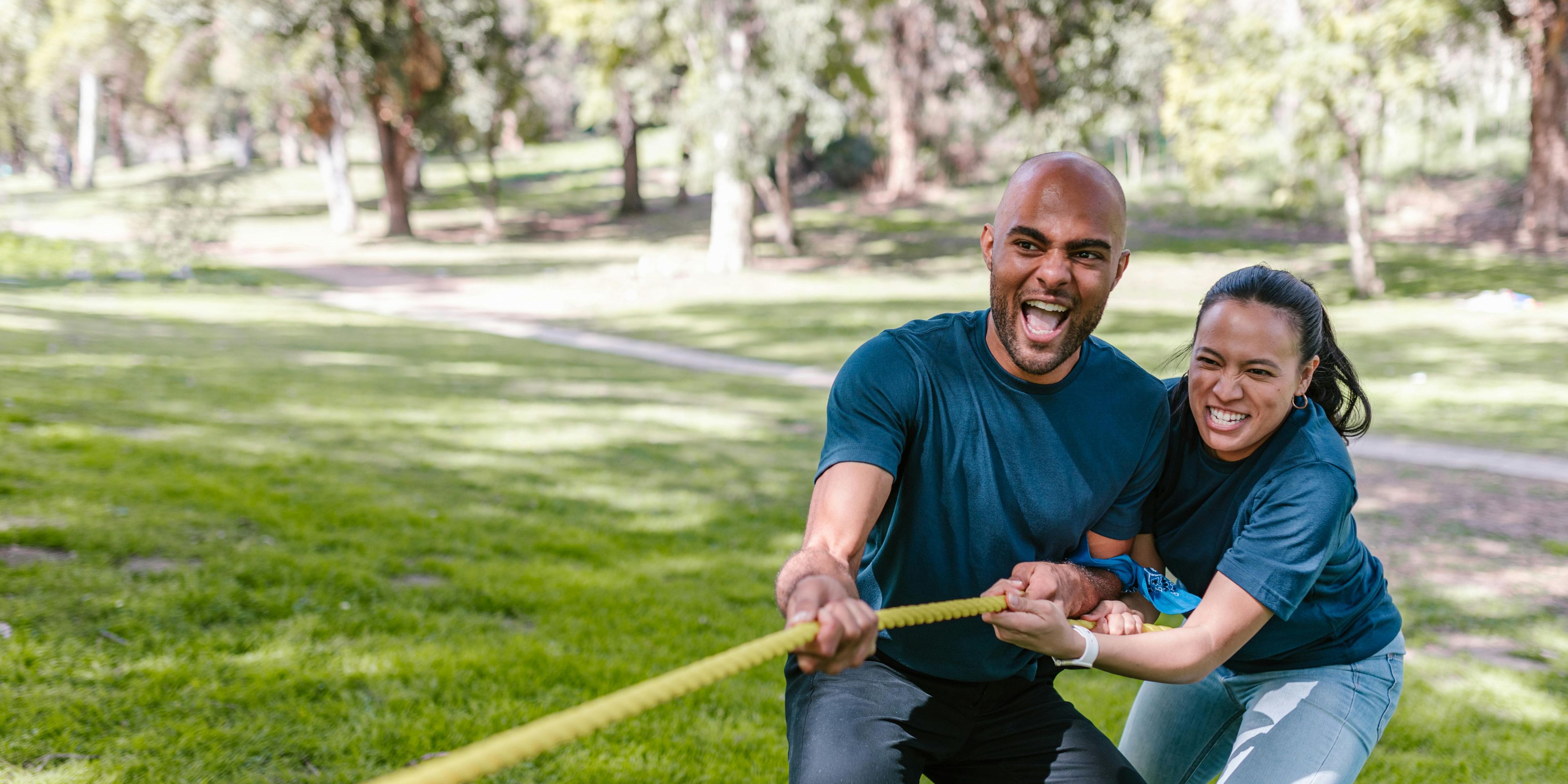 Couple with blue shirts and jeans pulling on a rope in tug-of-war