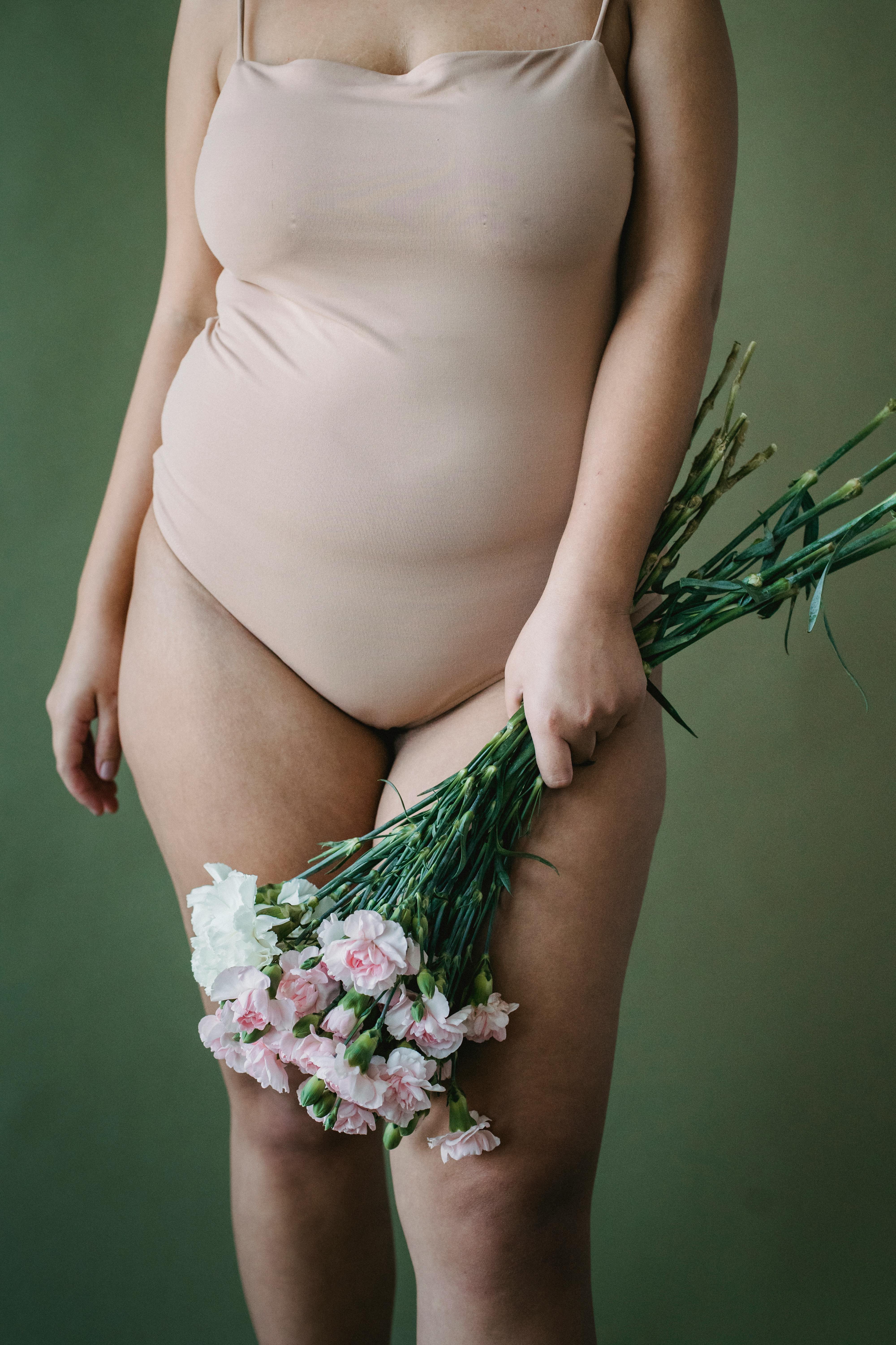 Woman in nude colored swimsuit holding a boquet of flowers