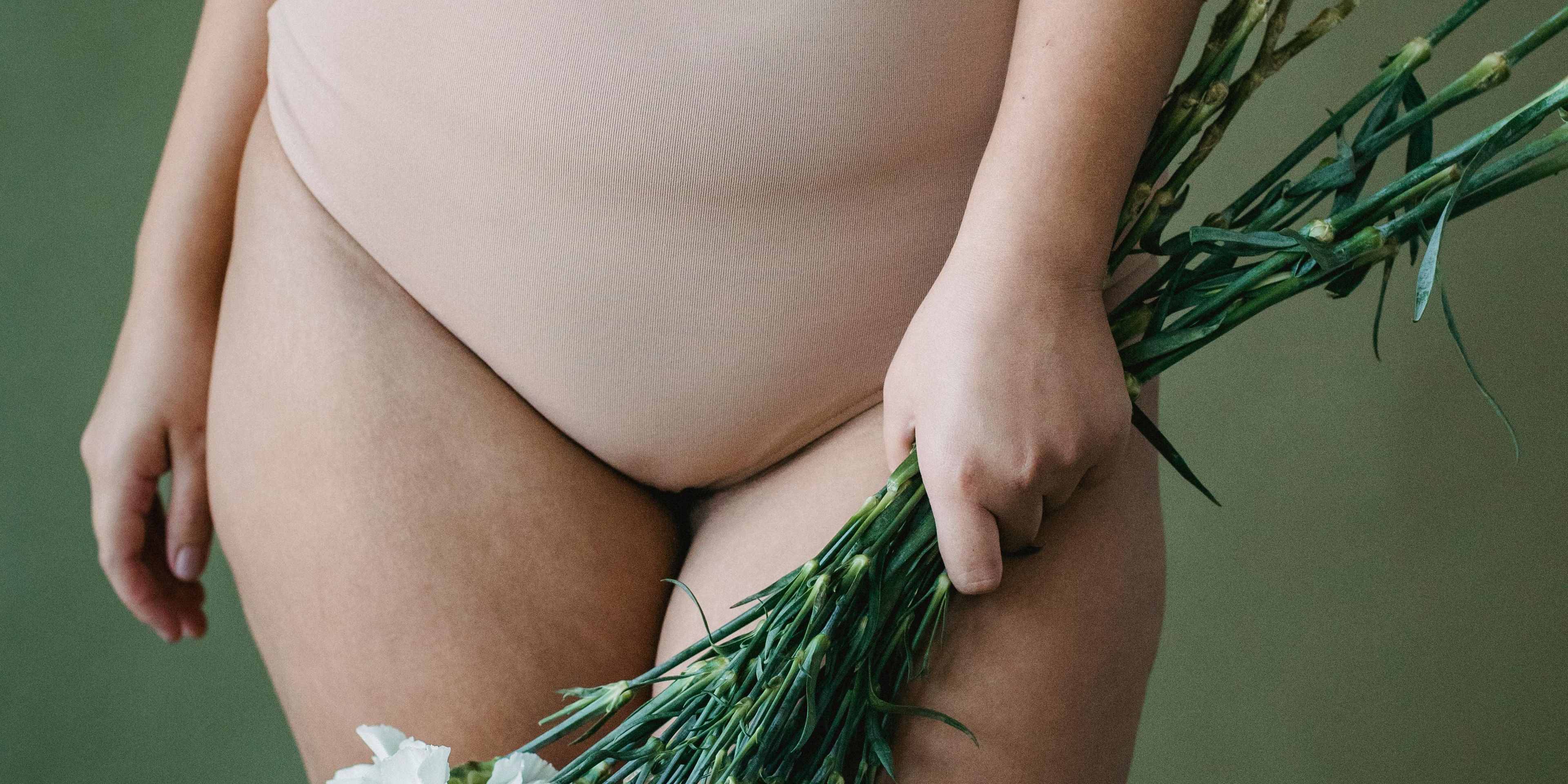 Woman in nude colored swimsuit holding a boquet of flowers