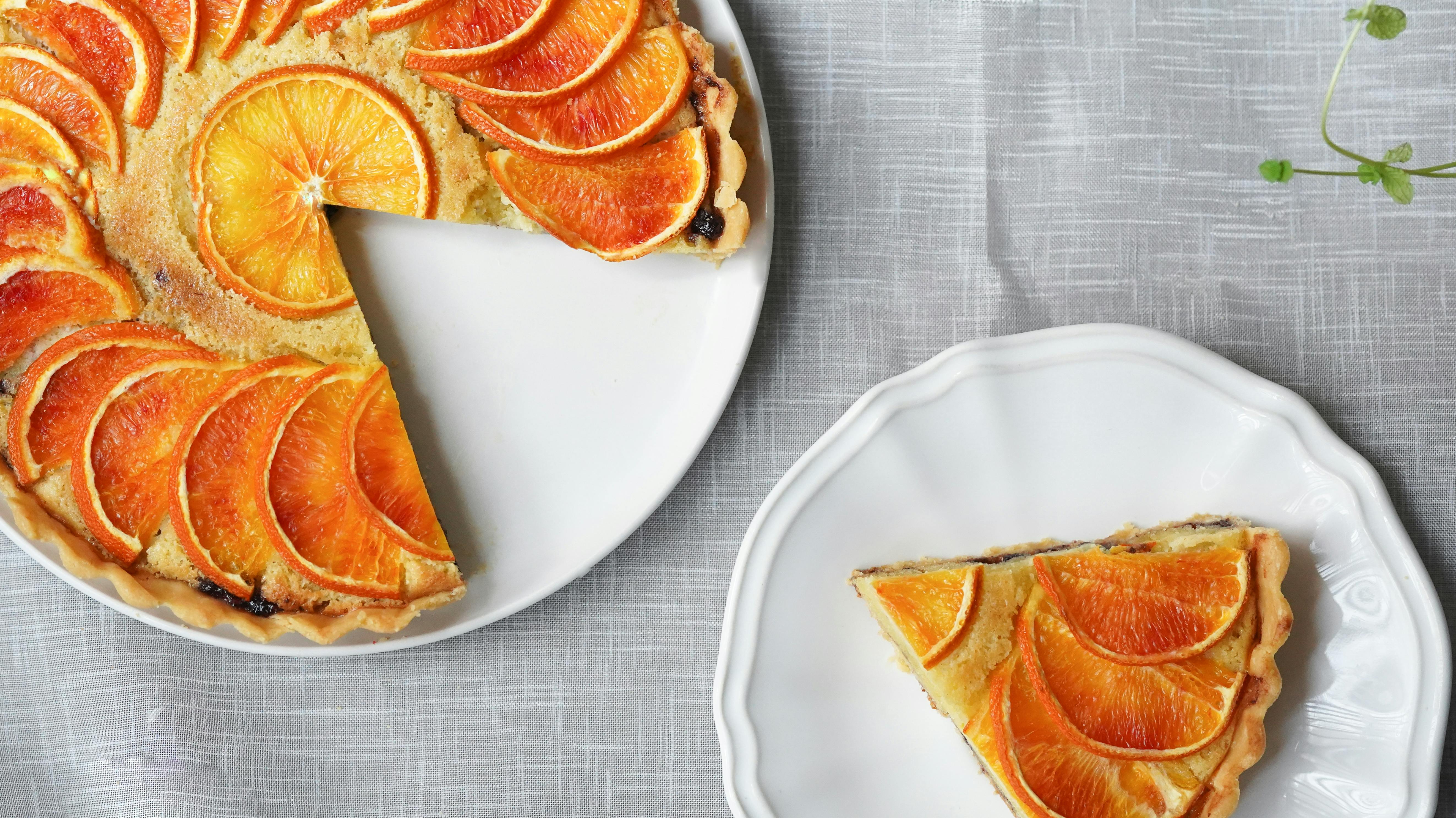 Orange pie garnished with orange slices with a slice taken out and on another plate