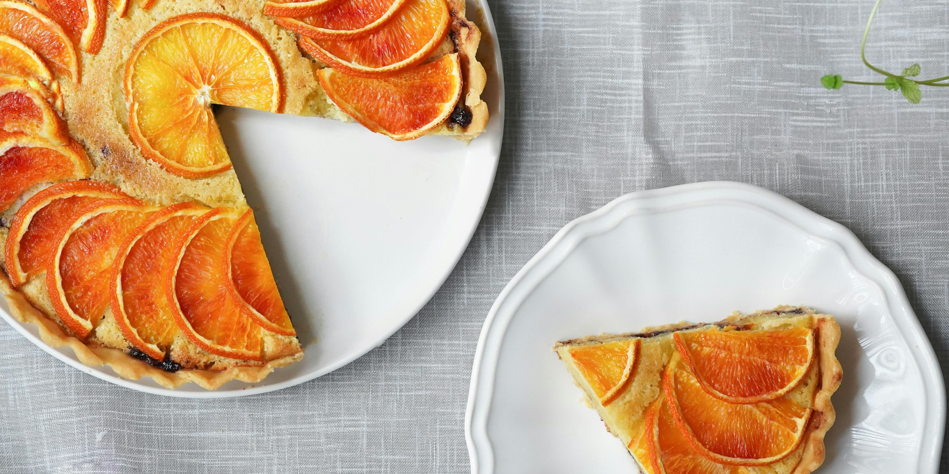 Orange pie garnished with orange slices with a slice taken out and on another plate
