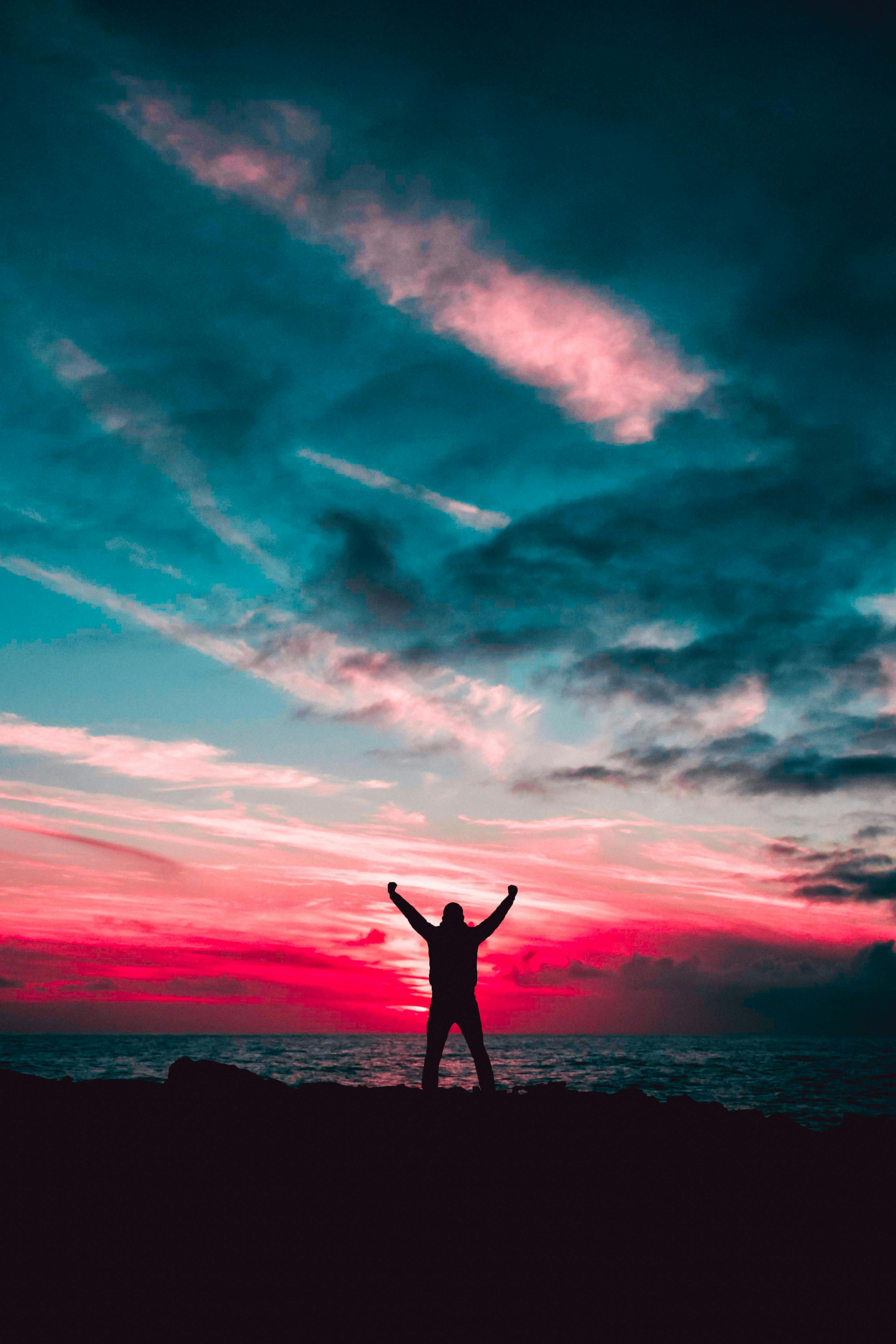 Person standing in front of a colorful sky celebrating