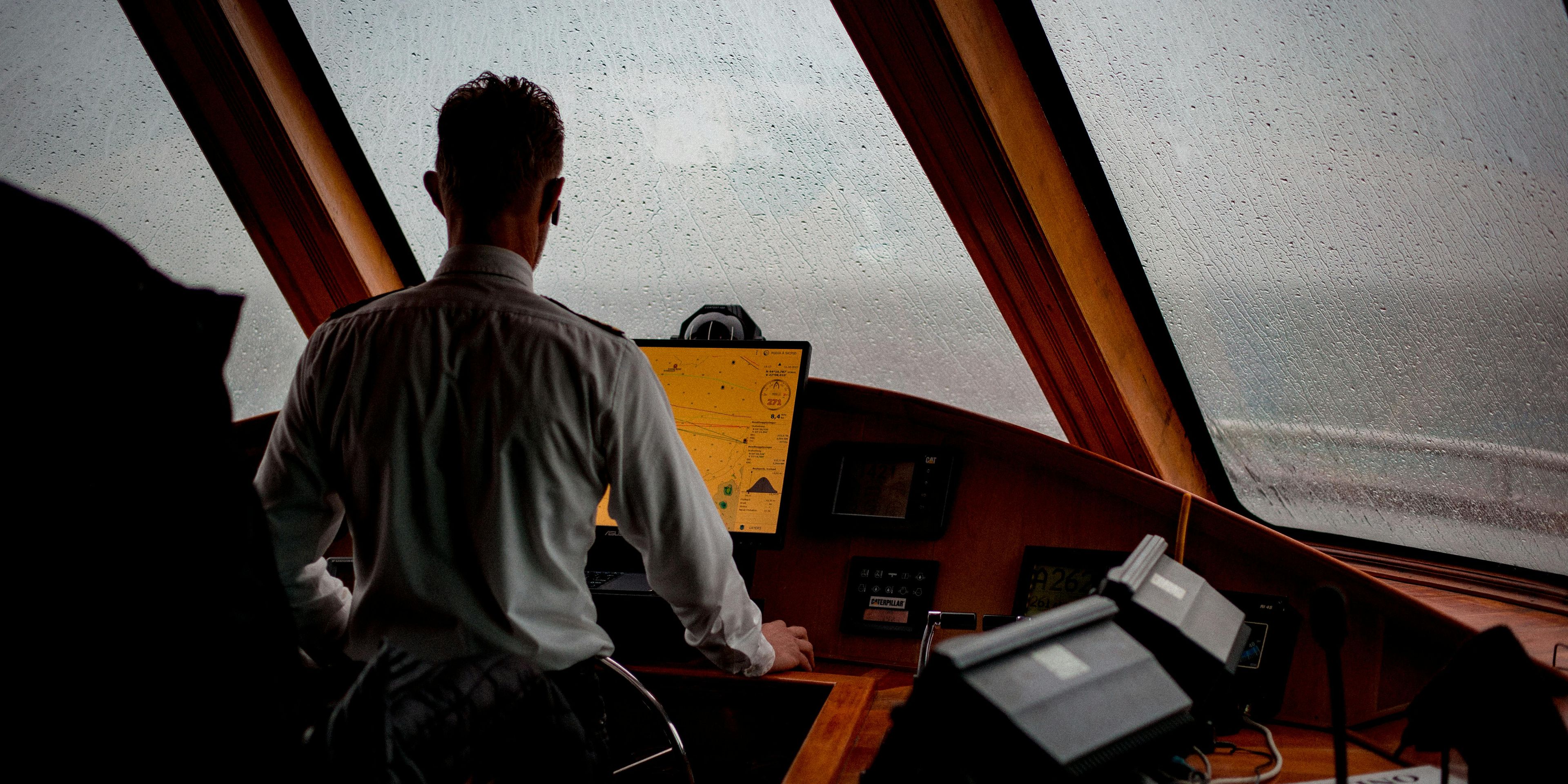Captain at the controls, navigating through rainy seas.