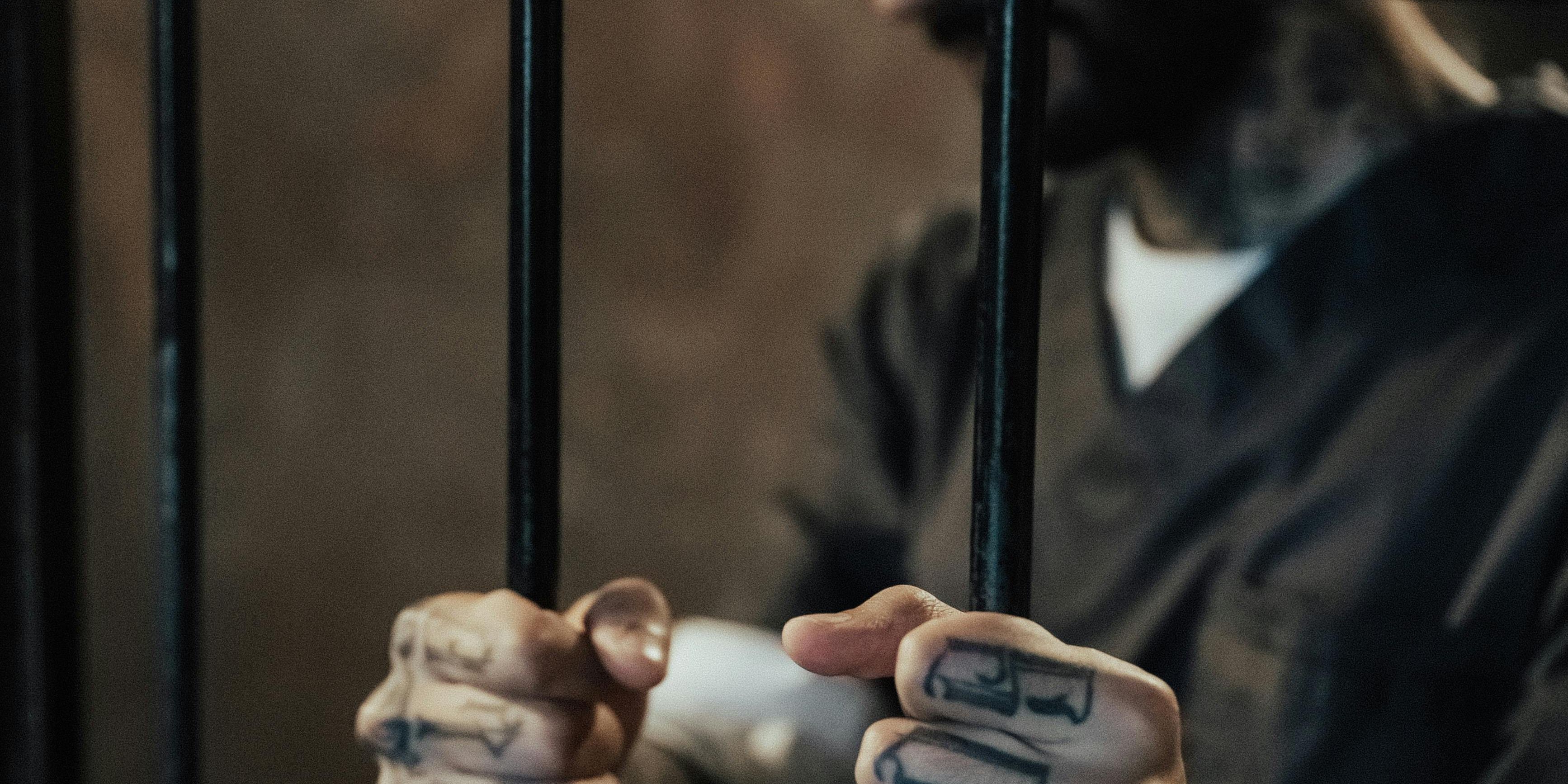 Guy in jail cell holding the bars