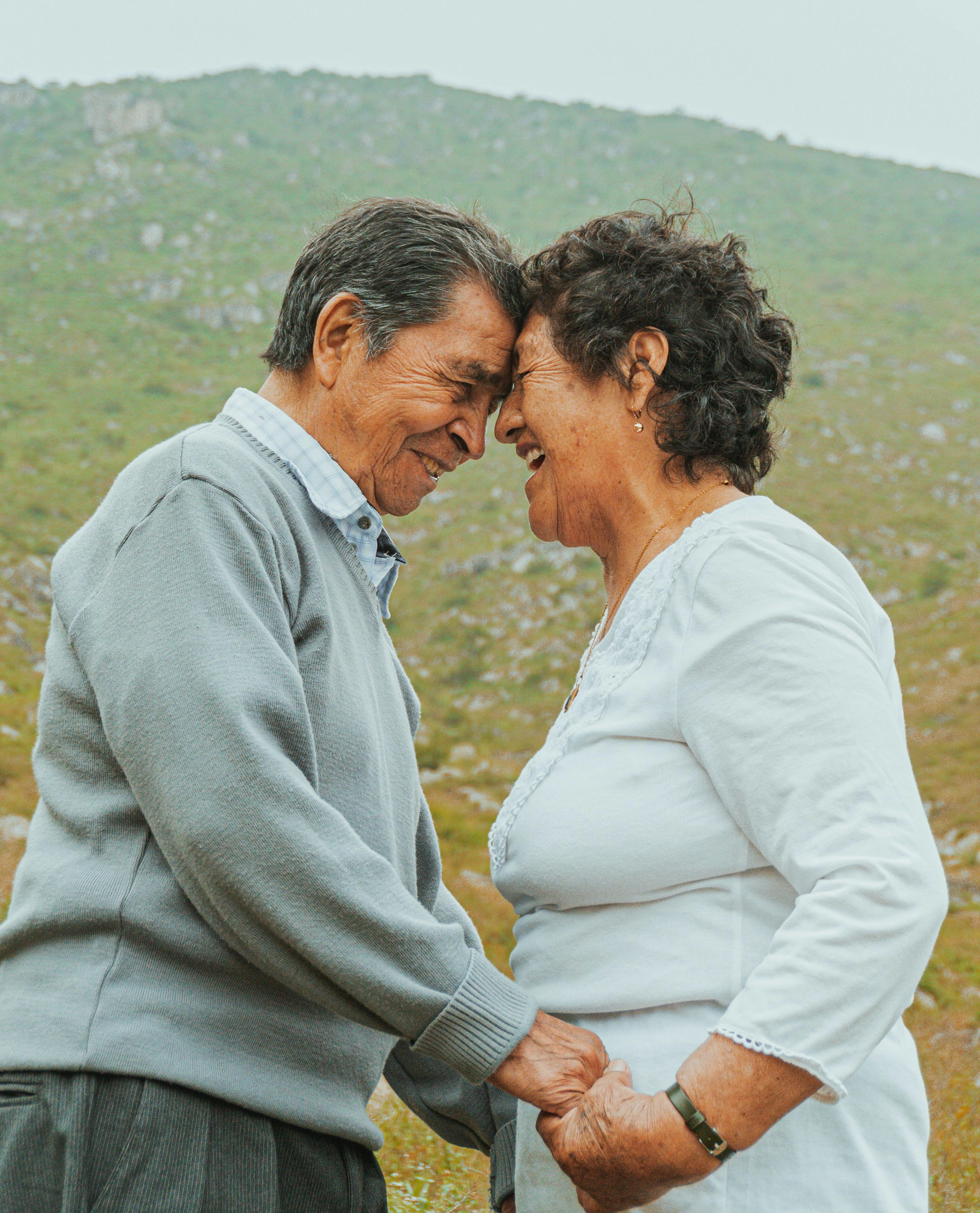 Older couple holding hands and intimately resting on each others foreheads 