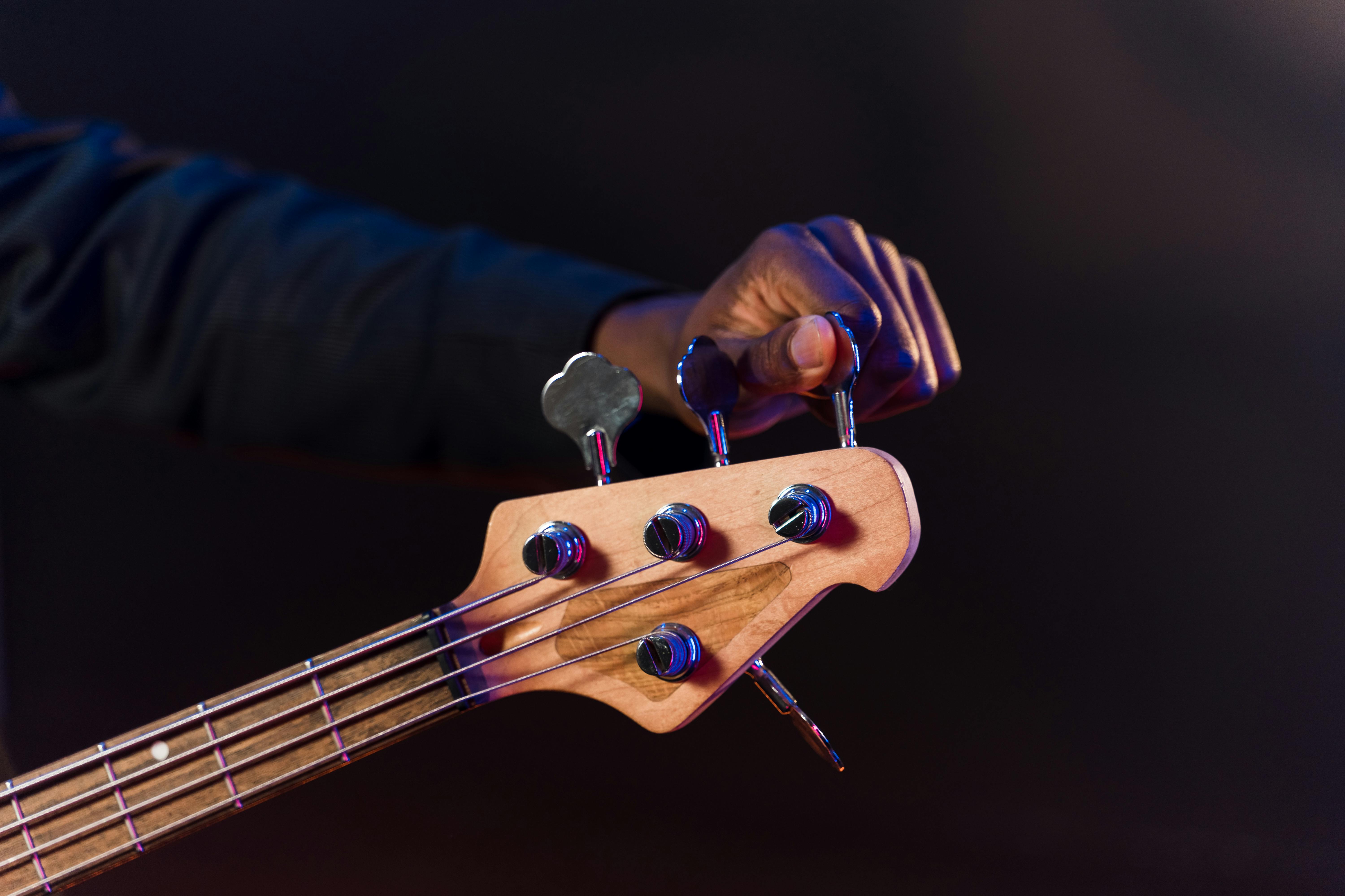 Person tuning a bass guitar