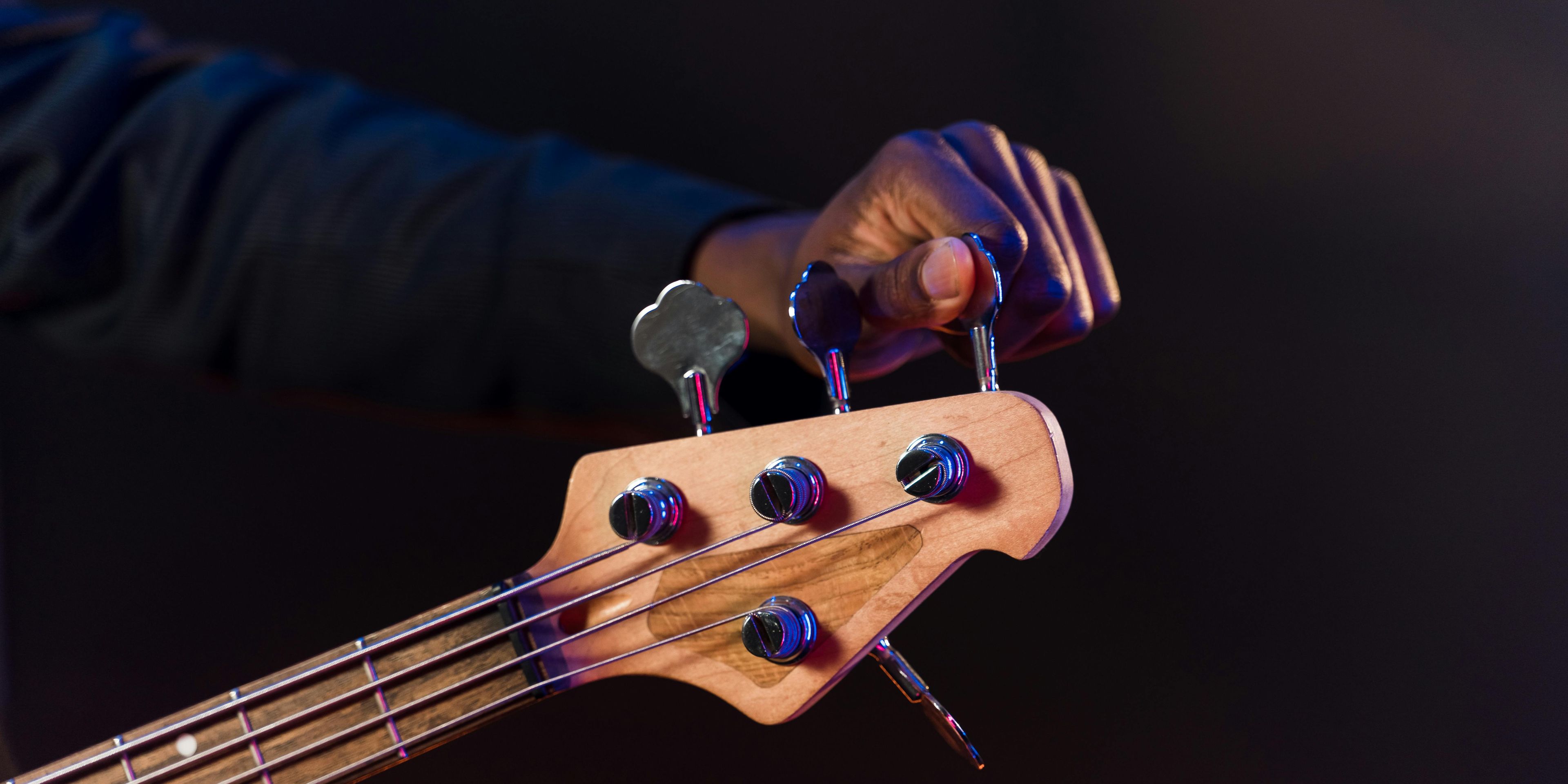 Person tuning a bass guitar