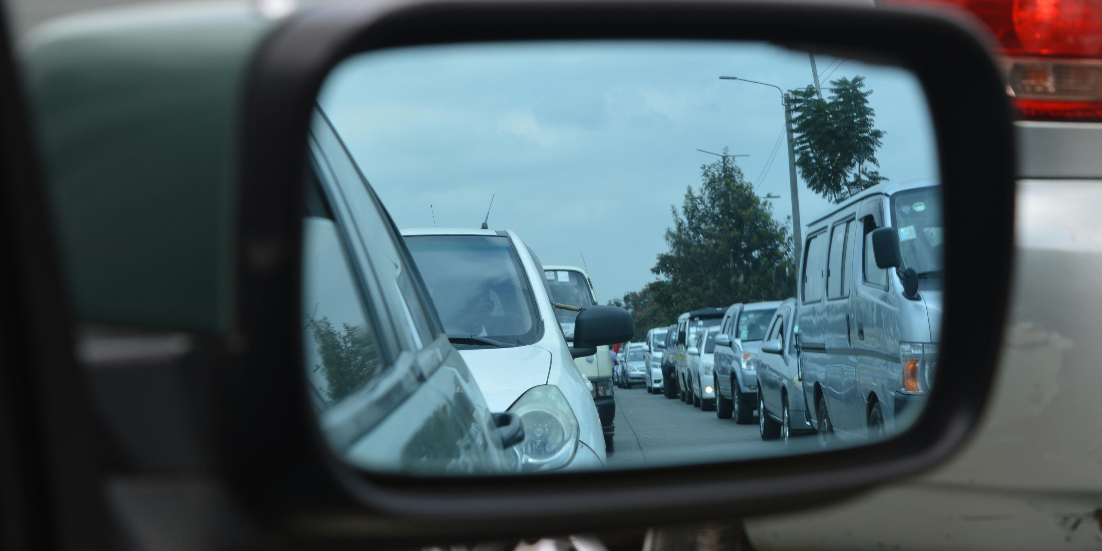 View of the rearview mirror showing a long line of traffic piling up