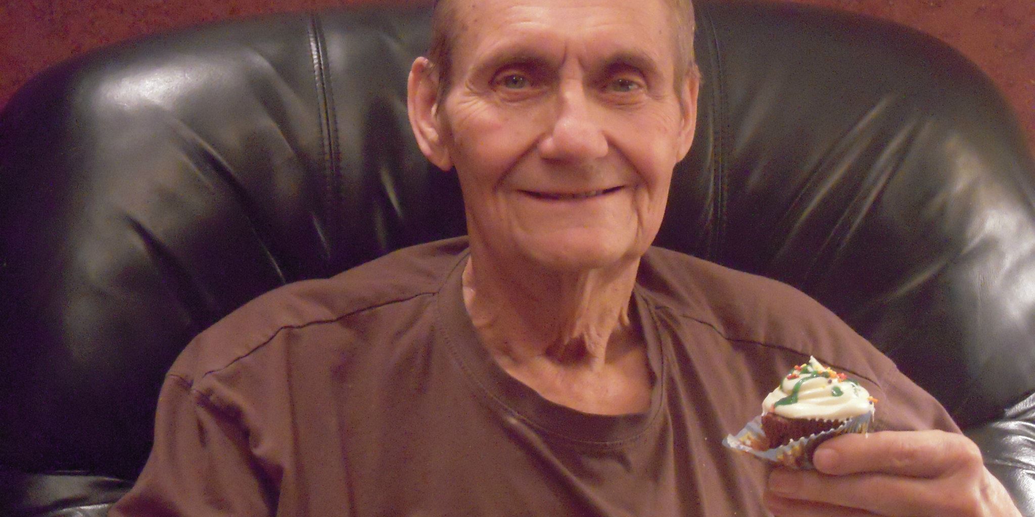 Old man sitting in his leather chair holding his cupcake
