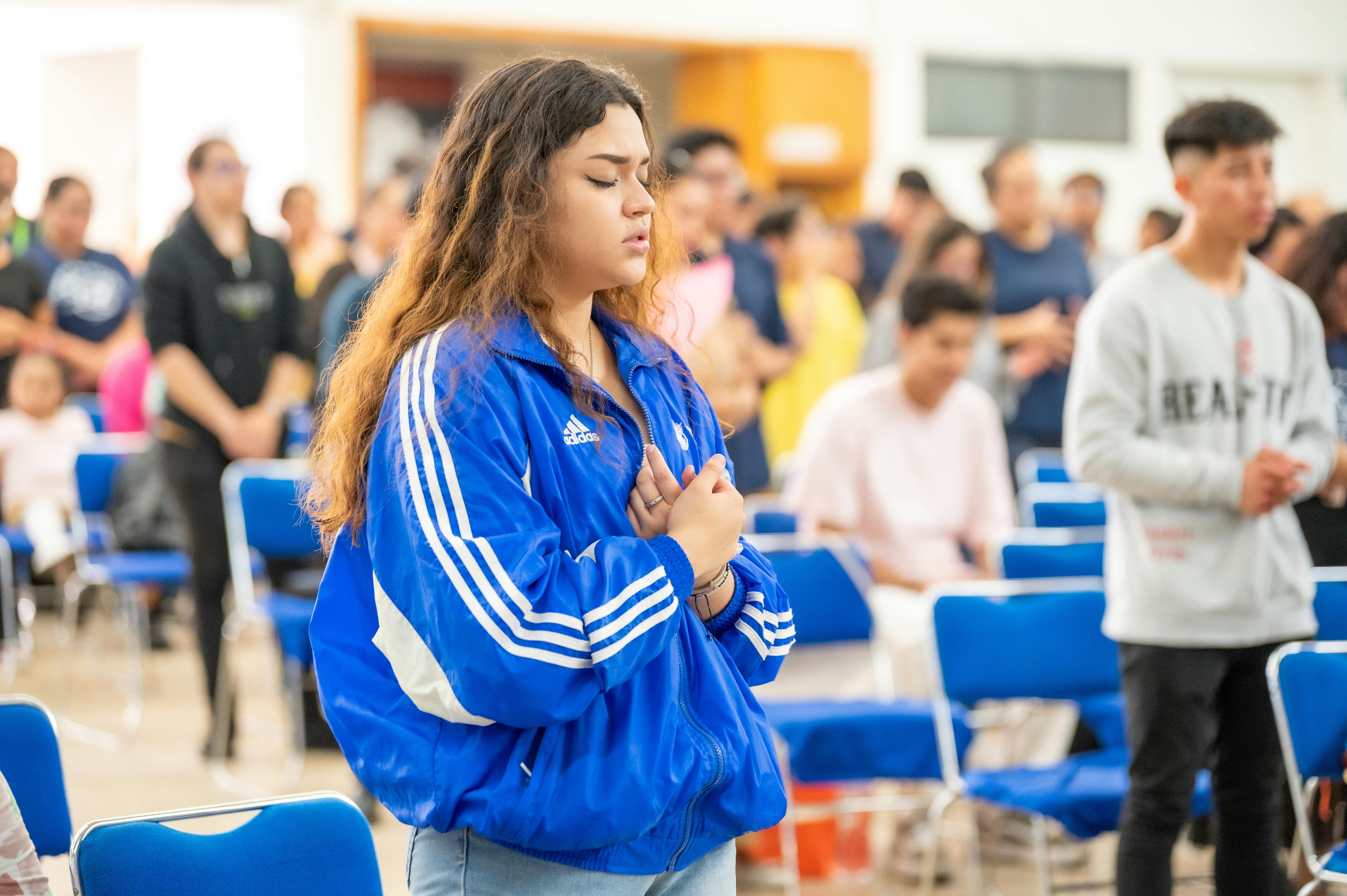 Young girl wearing a track sweater crossing her arms with her eyes closed