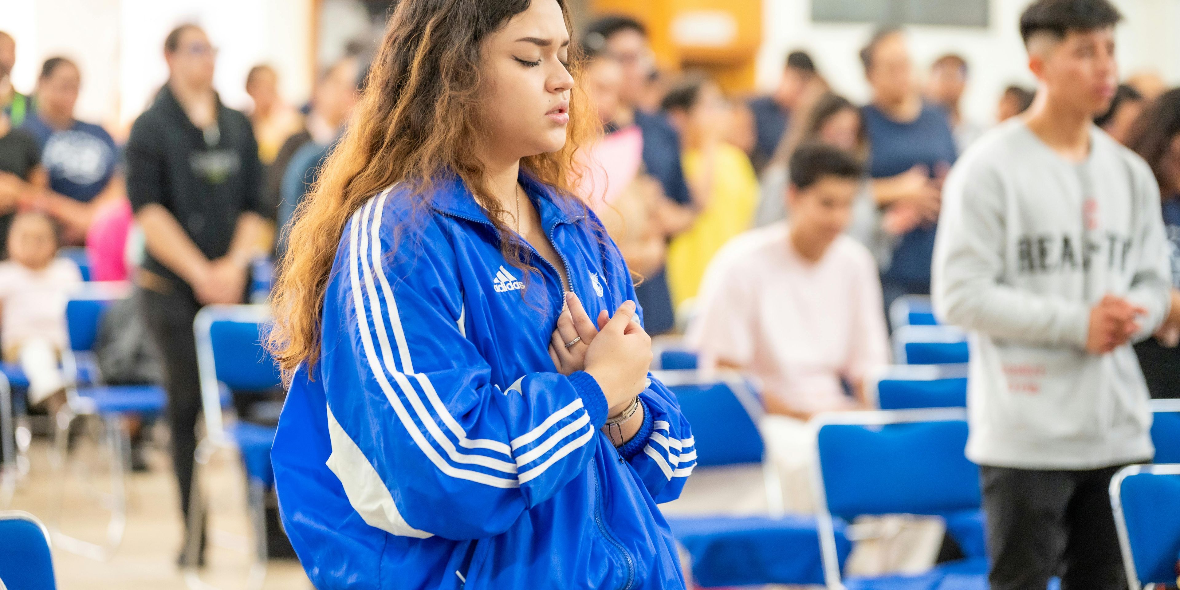 Young girl wearing a track sweater crossing her arms with her eyes closed