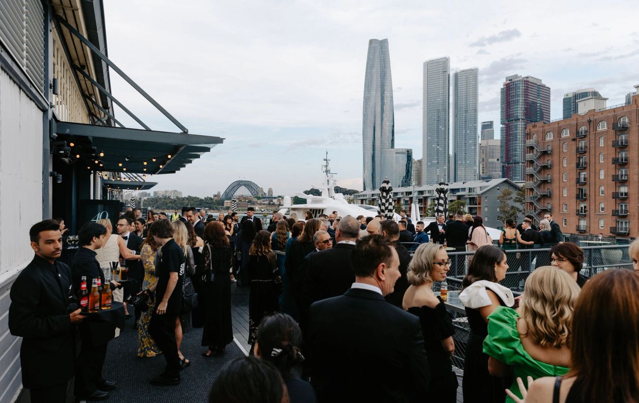 Black-tie guests at a rooftop reception overlooking the Sydney Harbour Bridge during the Timpelle Kitchens 40th anniversary