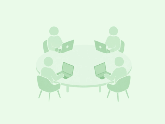 Four people sit around a round table, each working on a laptop.