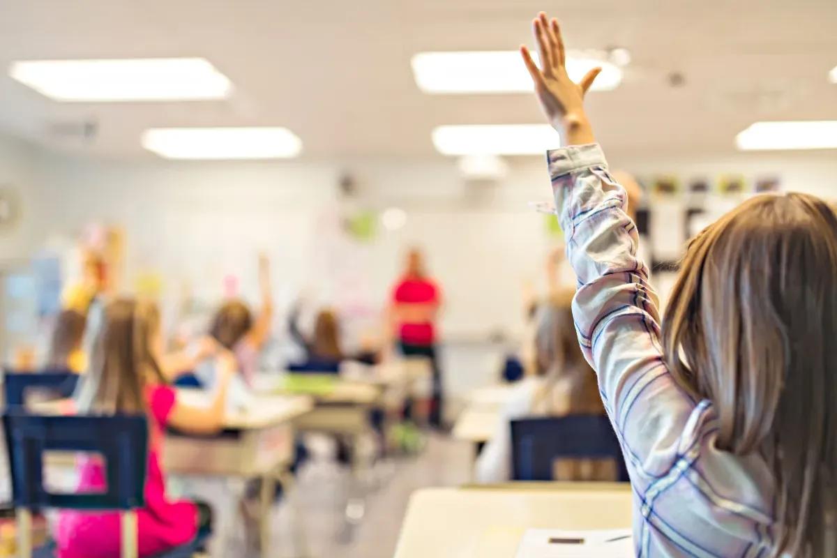 Una joven levanta la mano en el aula para responder a una pregunta