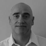 Black and white headshot of a bald man in a white collared shirt