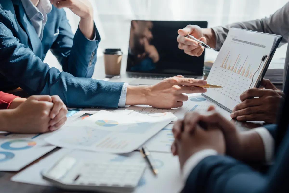 A group of business people are sitting around a table looking at a graph