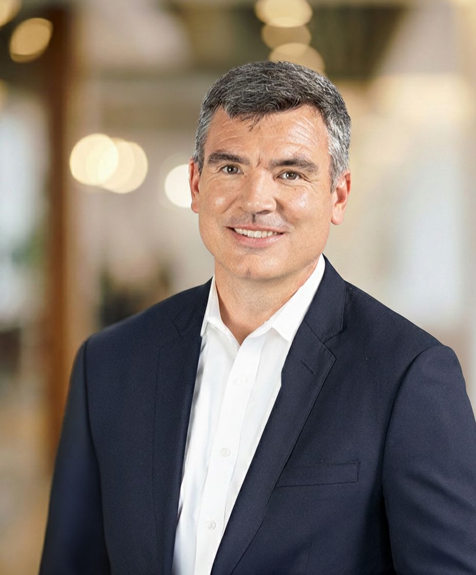 A man in a suit and white shirt smiles for the camera