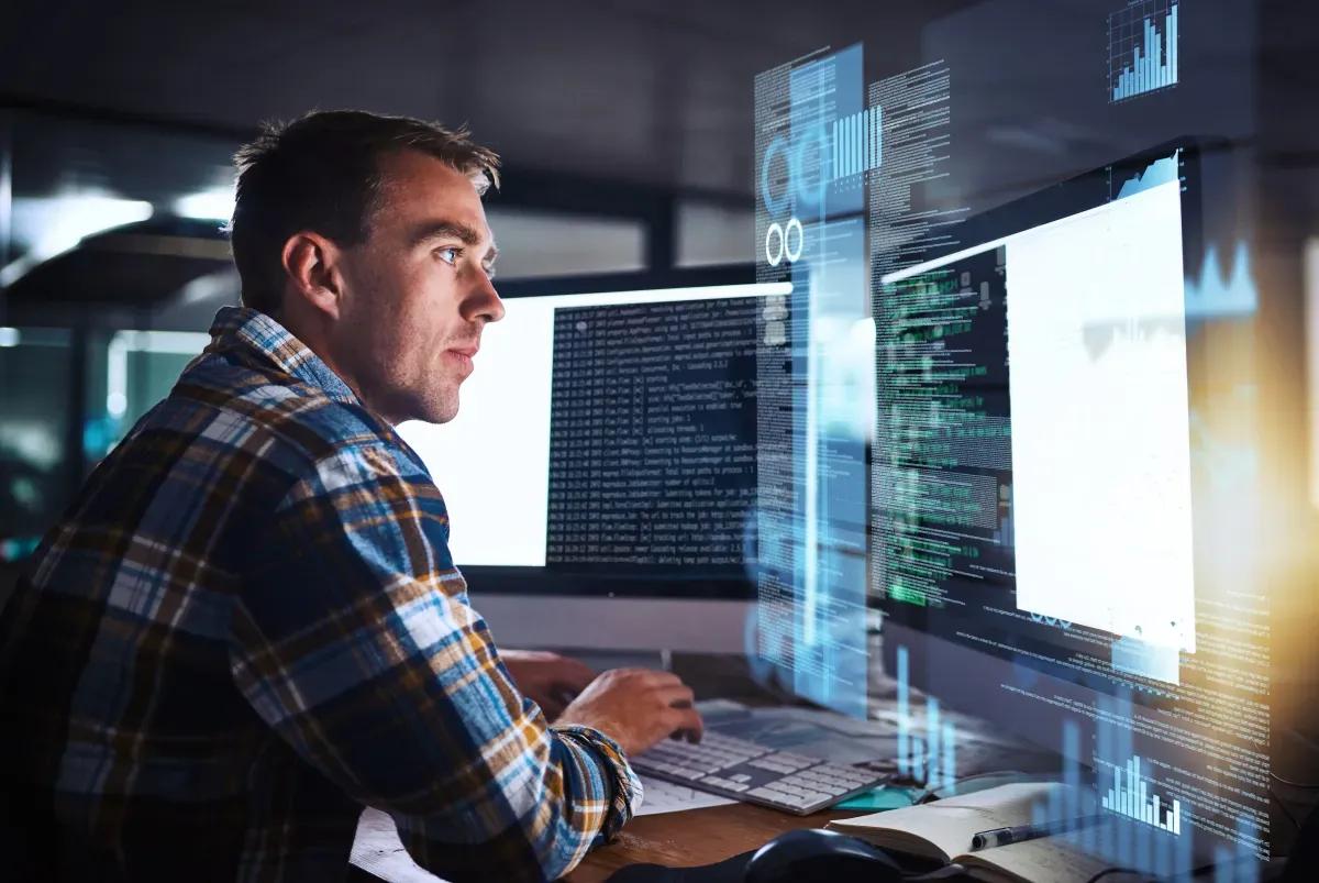 Ein mann sitzt an einem schreibtisch und blickt auf einen computerbildschirm