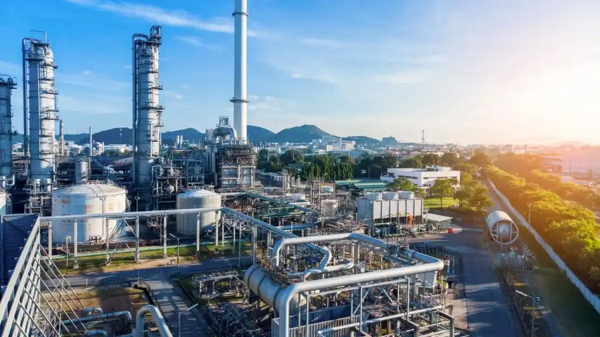 An aerial view of a large oil refinery with a city in the background