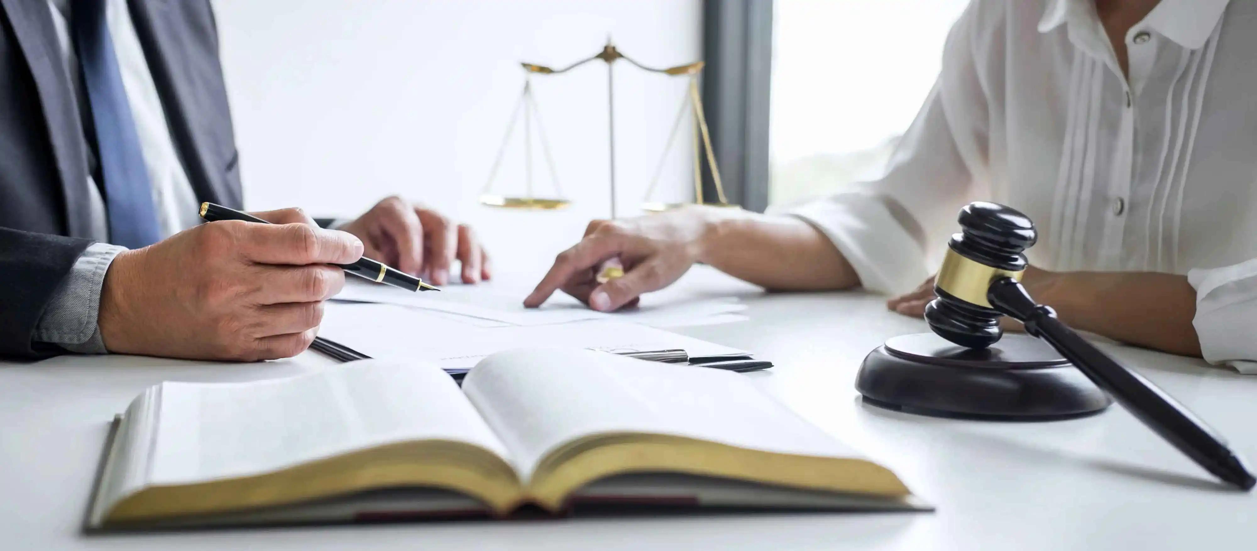 A man and a woman are sitting at a table with a book and a gavel
