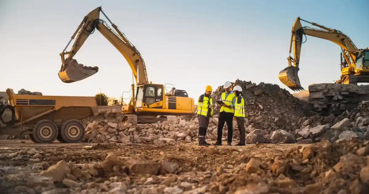 A group of construction workers are standing in front of a pile of rocks