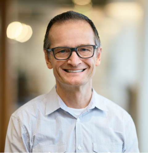 A man in a white shirt is smiling for the camera