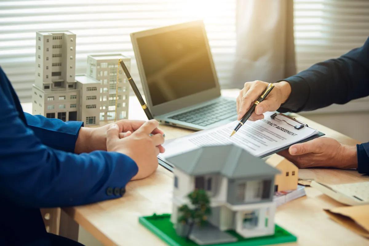 Dois homens esto sentados mesa assinando um contrato para uma casa