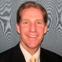 A man in a suit and tie is smiling for the camera