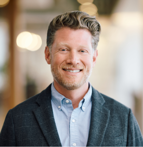 A man in a suit and blue shirt smiles for the camera