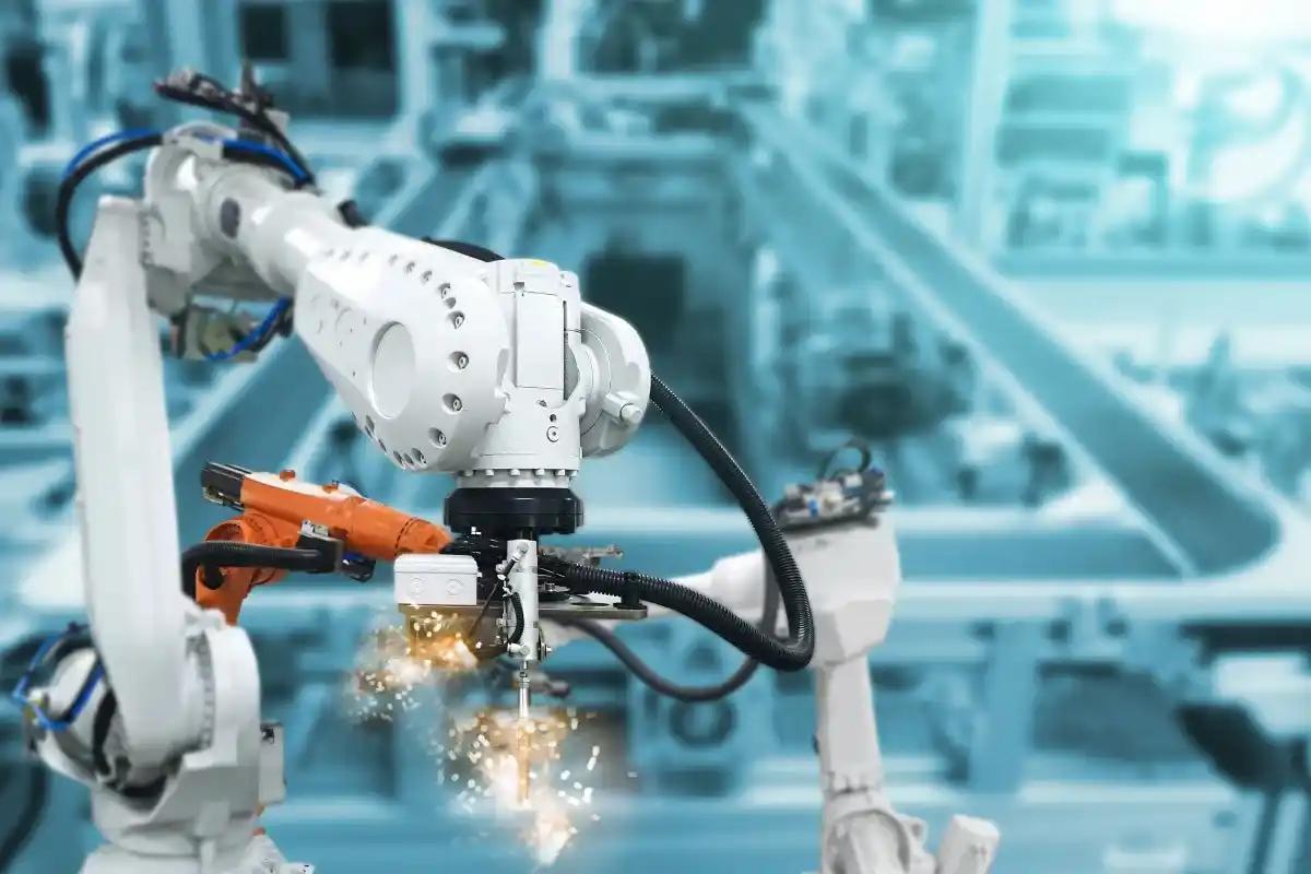 A robotic arm is cutting a piece of metal in a factory