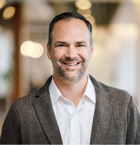 A man in a suit and white shirt smiles for the camera