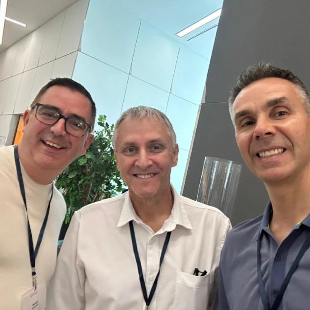Three men are posing for a picture together and smiling for the camera
