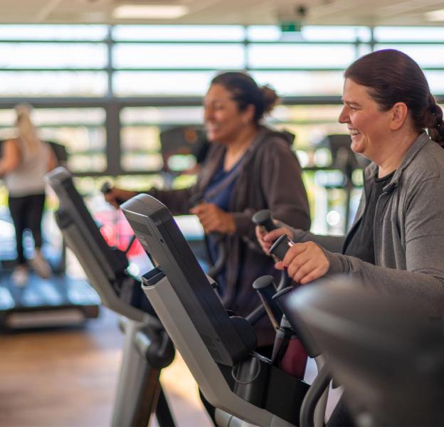 Duas mulheres esto pedalando bicicletas ergomtricas em uma academia