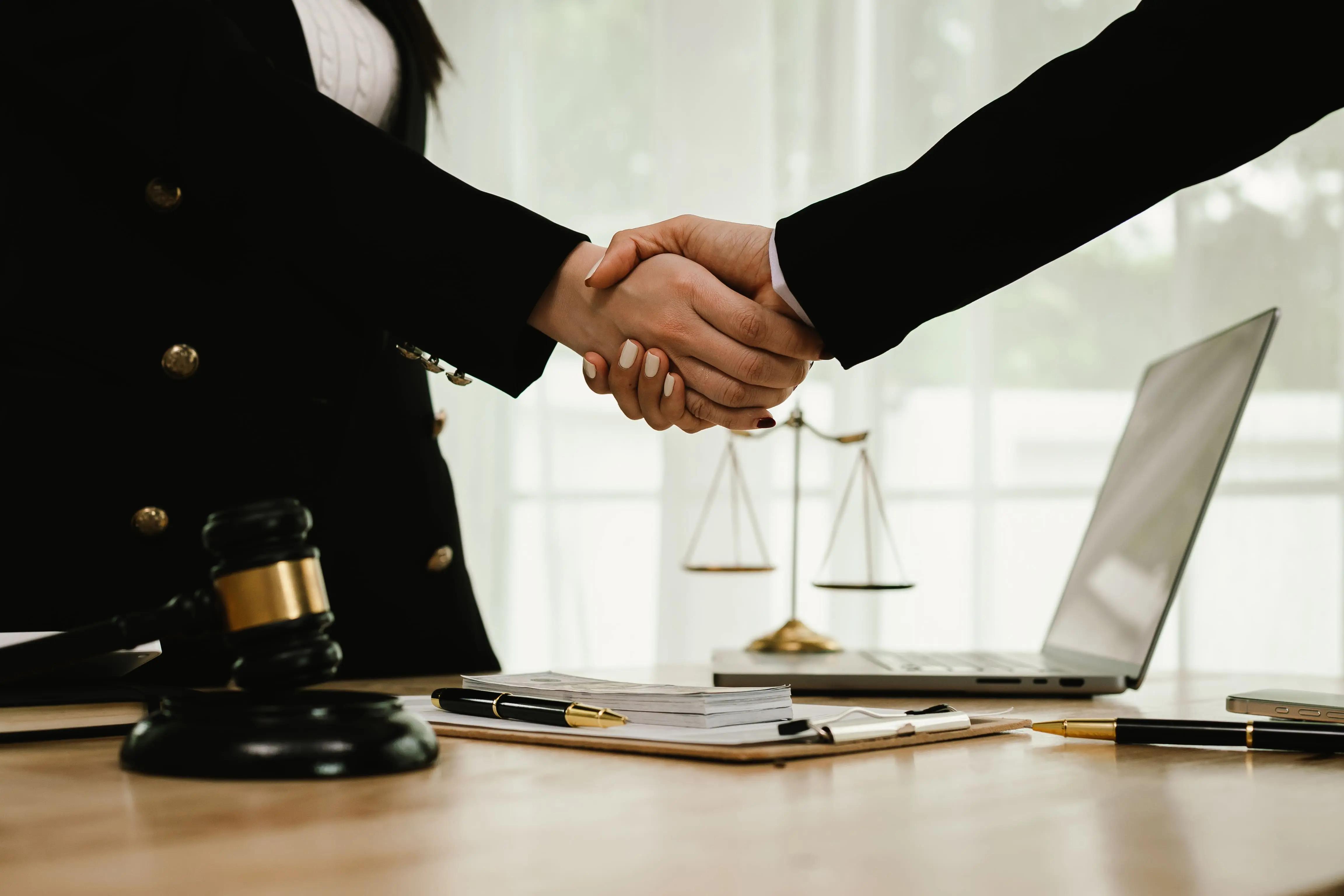 A lawyer and a client are shaking hands in a courtroom