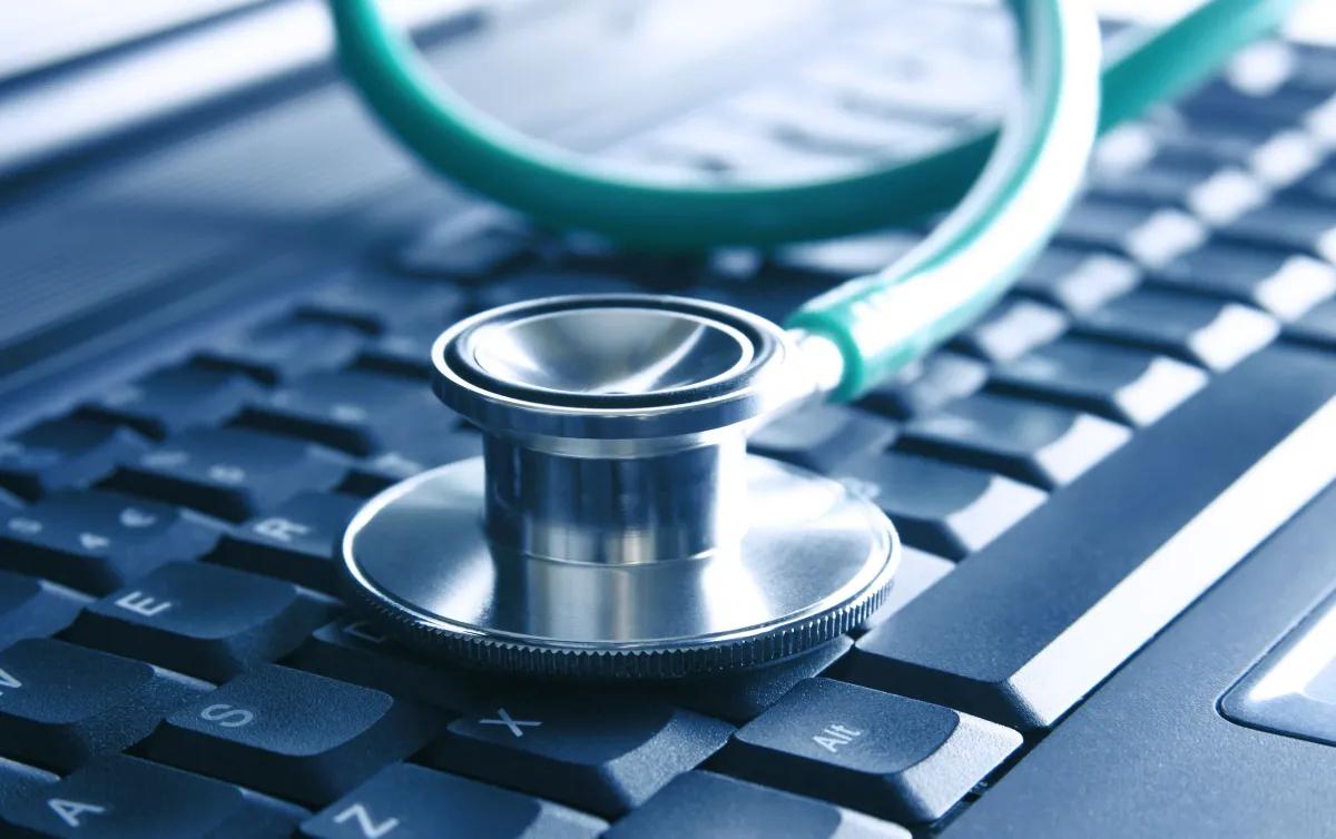 Um estetoscpio est em cima de um teclado de laptop