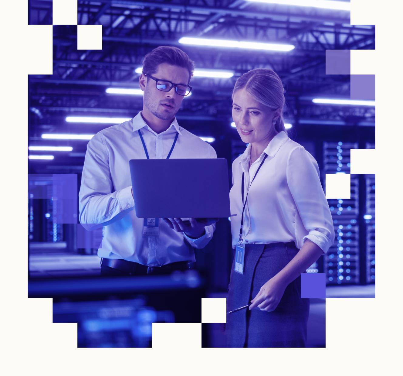 A man and a woman are looking at a laptop in a server room