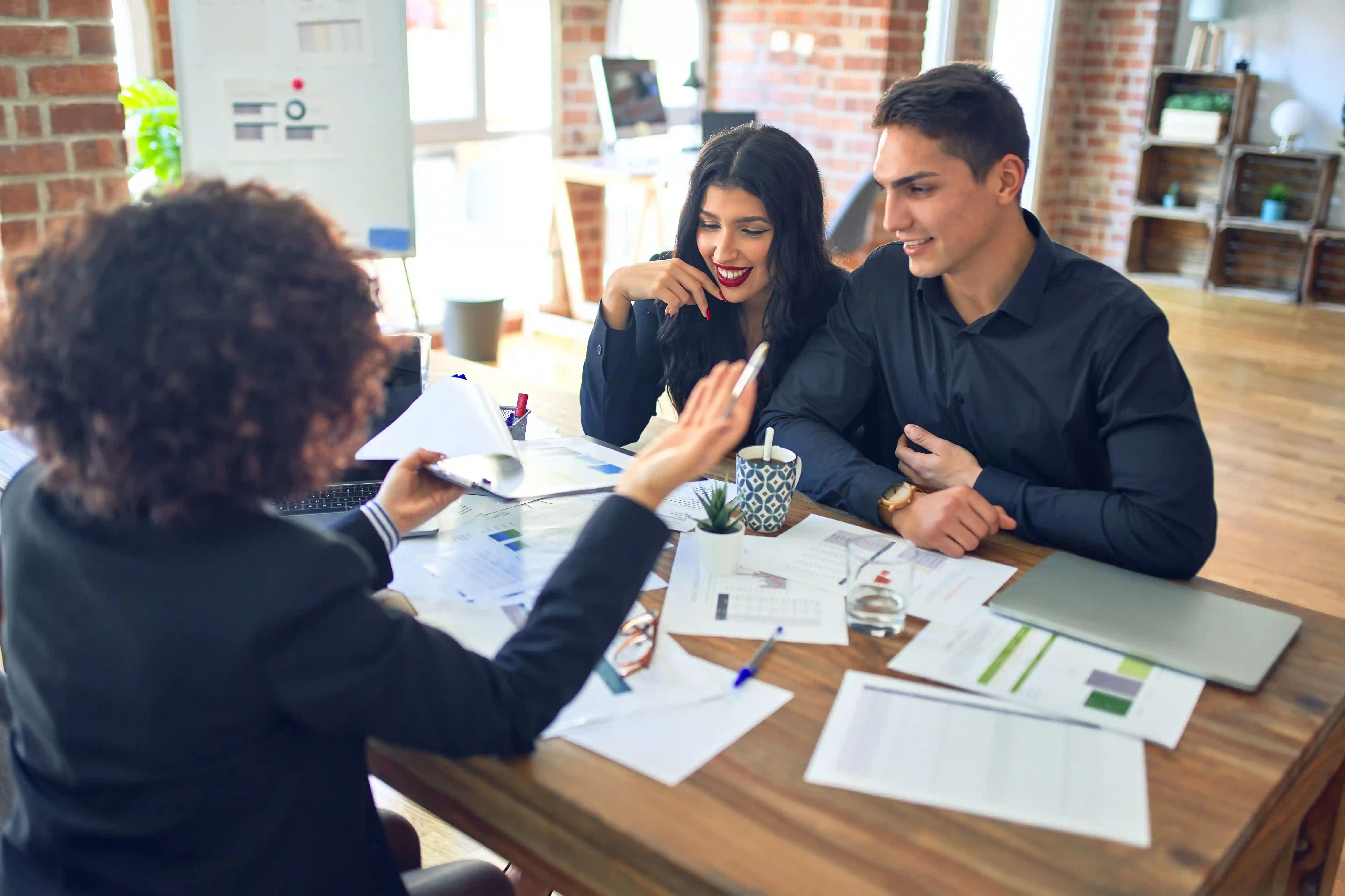 A man and a woman are sitting at a table looking at a clipboard with graphs on it