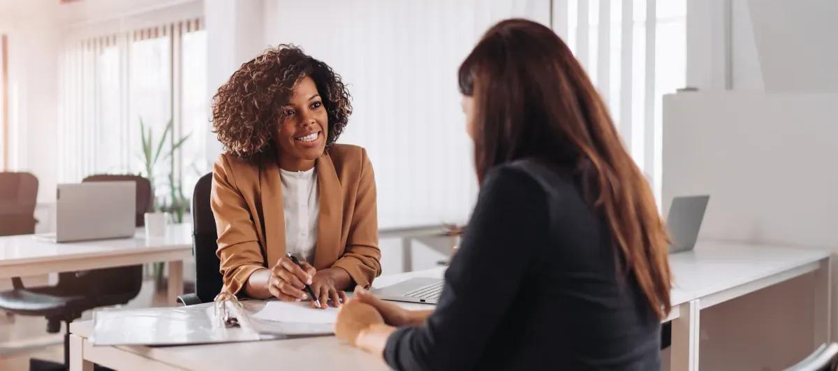 Two women are sitting at a table having a job interview