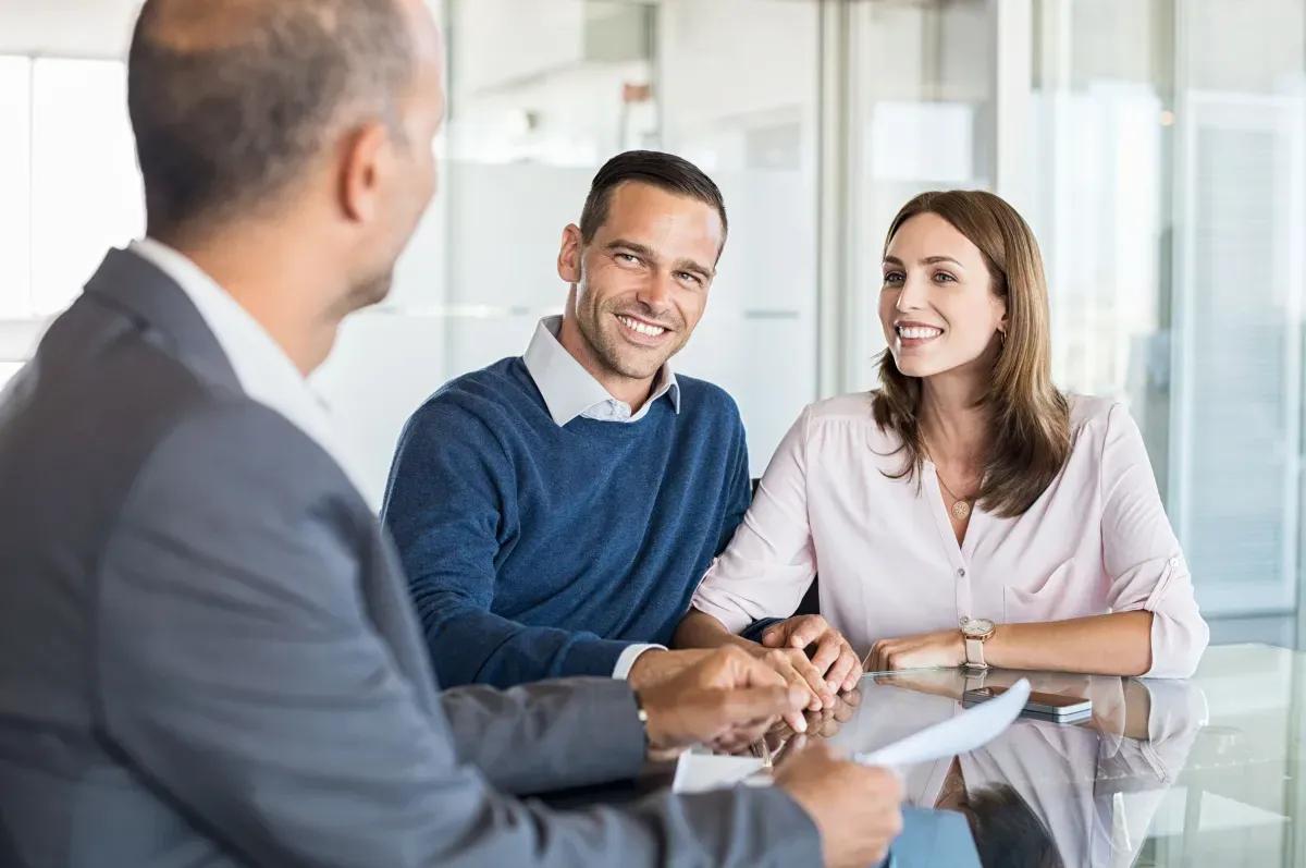 A man and a woman are sitting at a table talking to a man