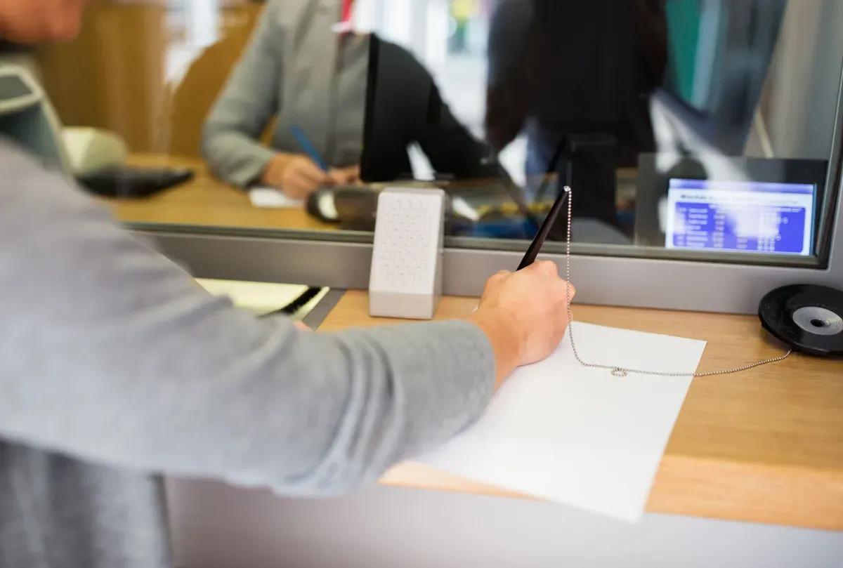 A man is signing a document at a bank counter