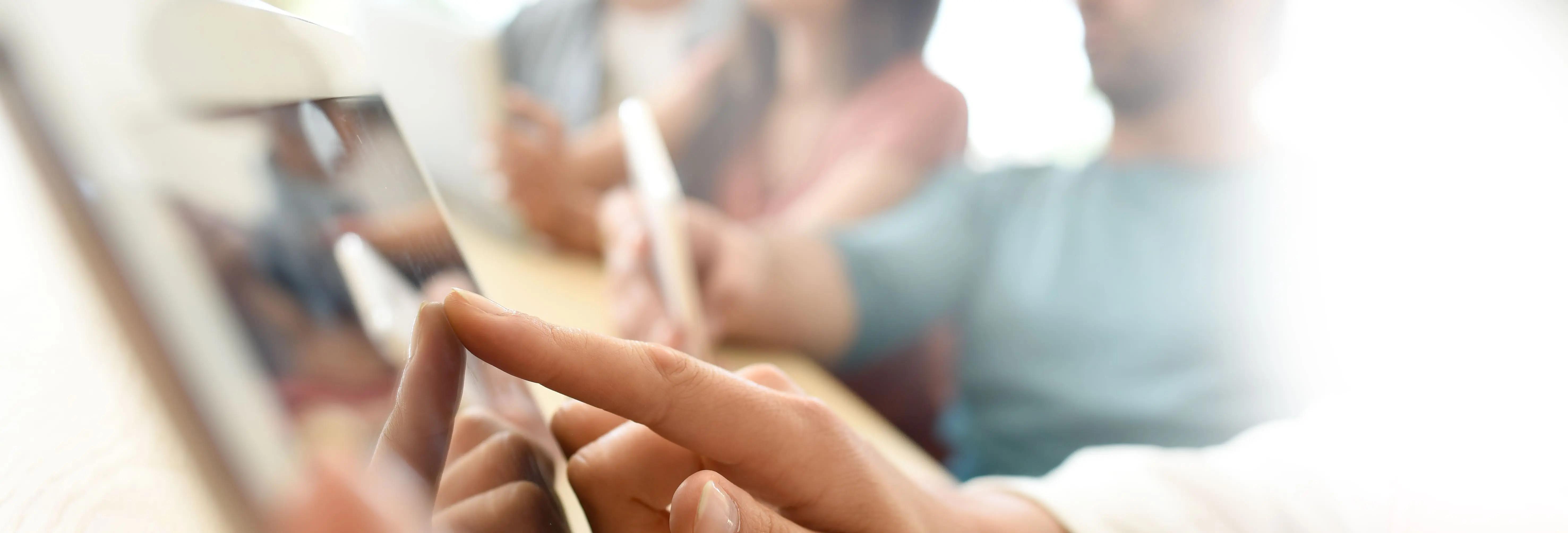 A person is pointing at a tablet with their finger
