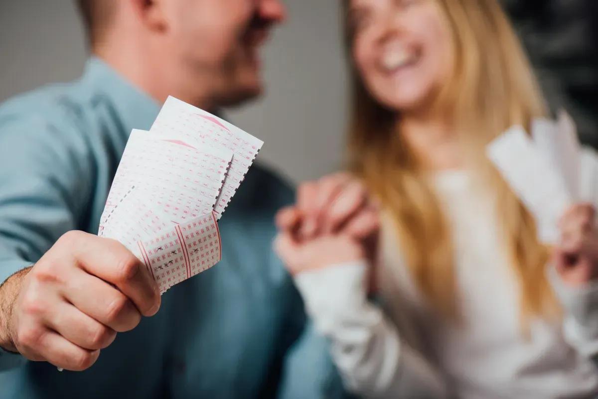 A man is holding a pile of lottery tickets in front of a woman