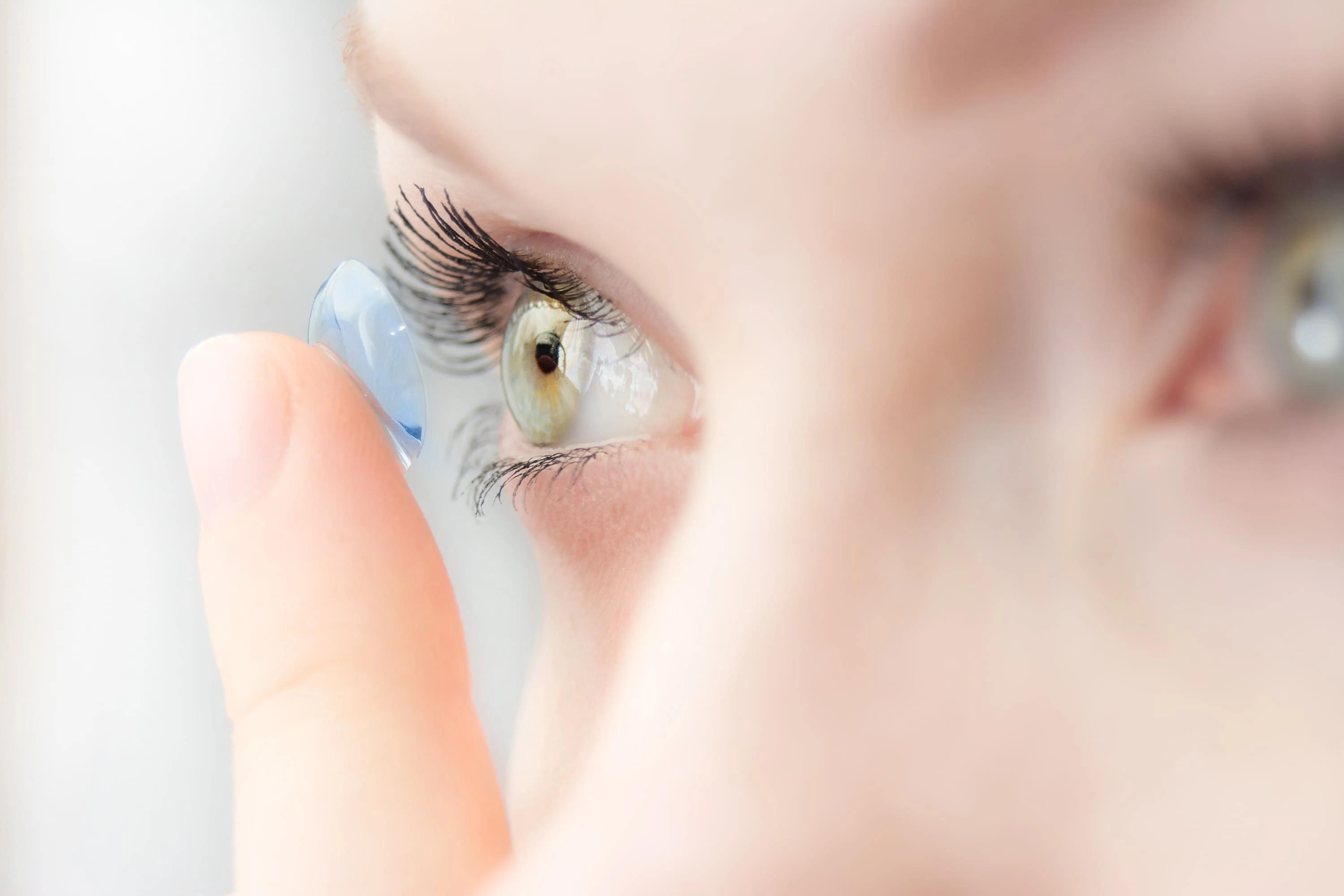 A woman is putting a contact lens in her eye