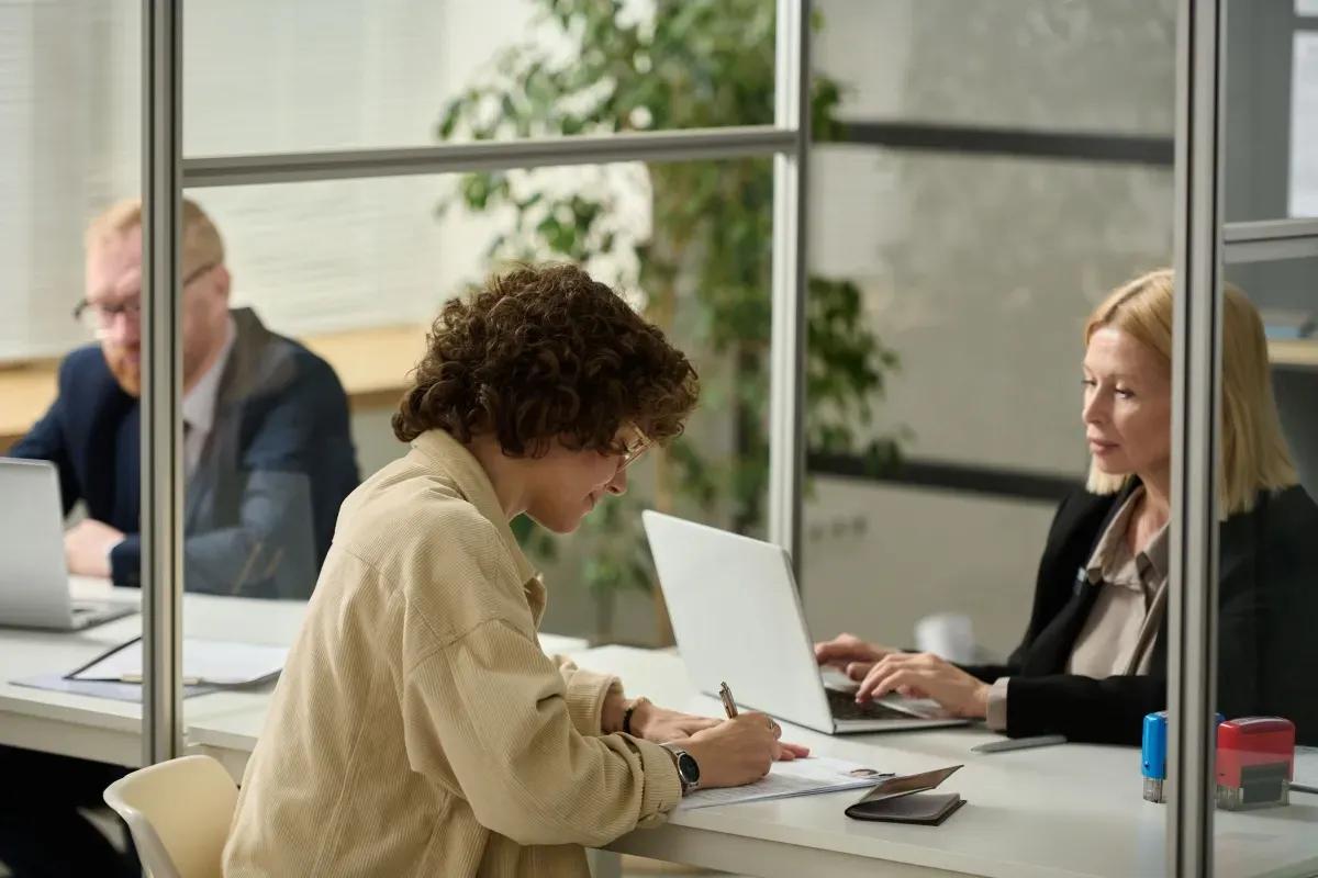 A group of people are sitting at a table with laptops