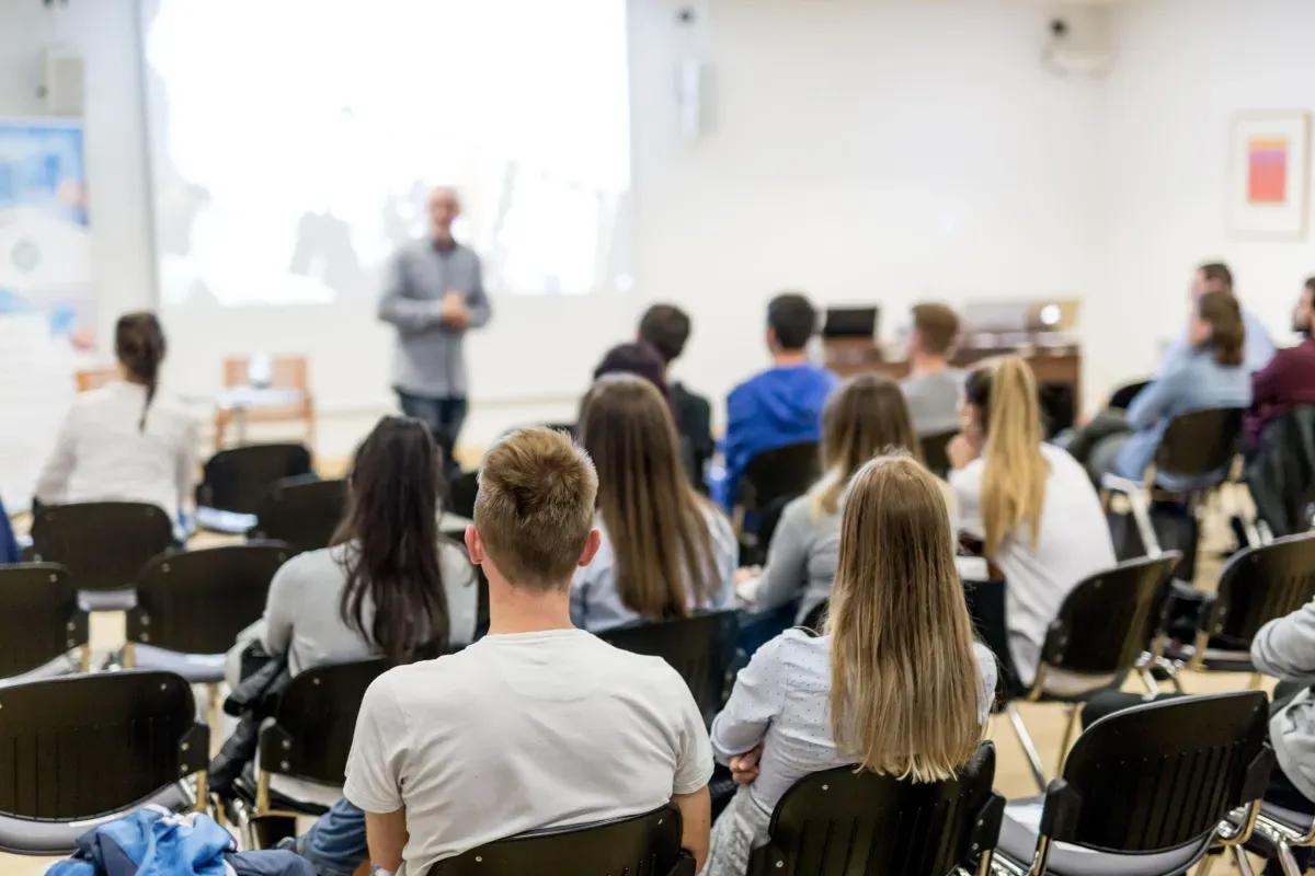 A group of people are sitting in a classroom listening to a lecture